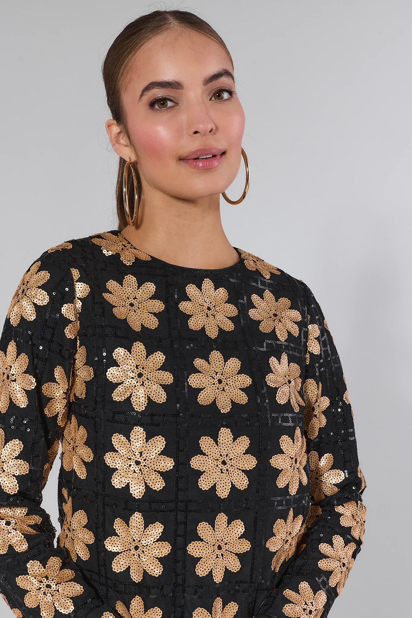 Woman wearing a Claudia Sequin Floral Mini Dress against a plain background