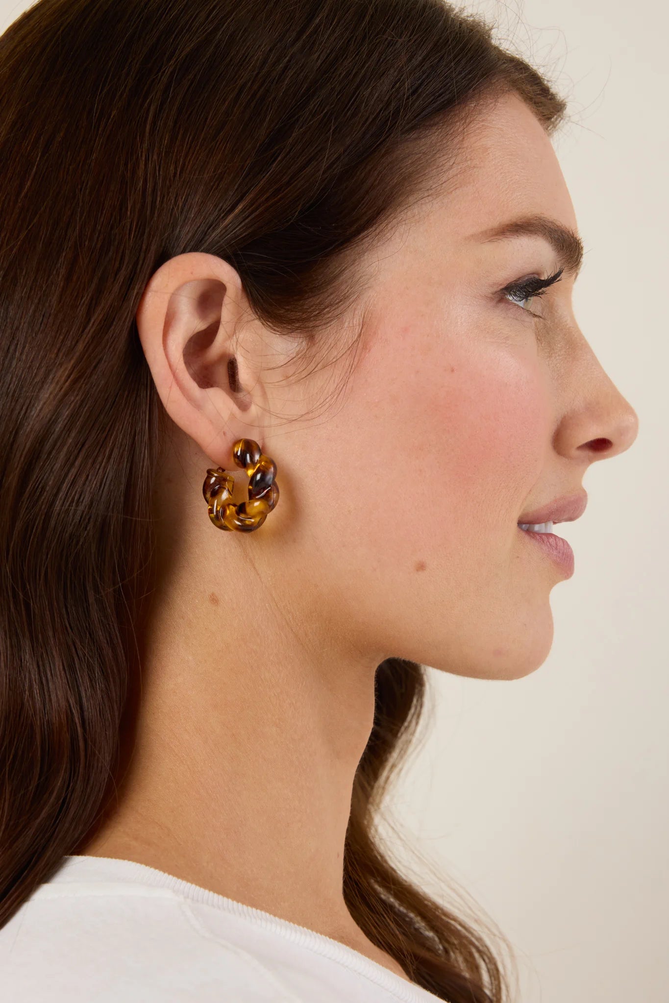Woman wearing a pair of earrings with a neutral background
