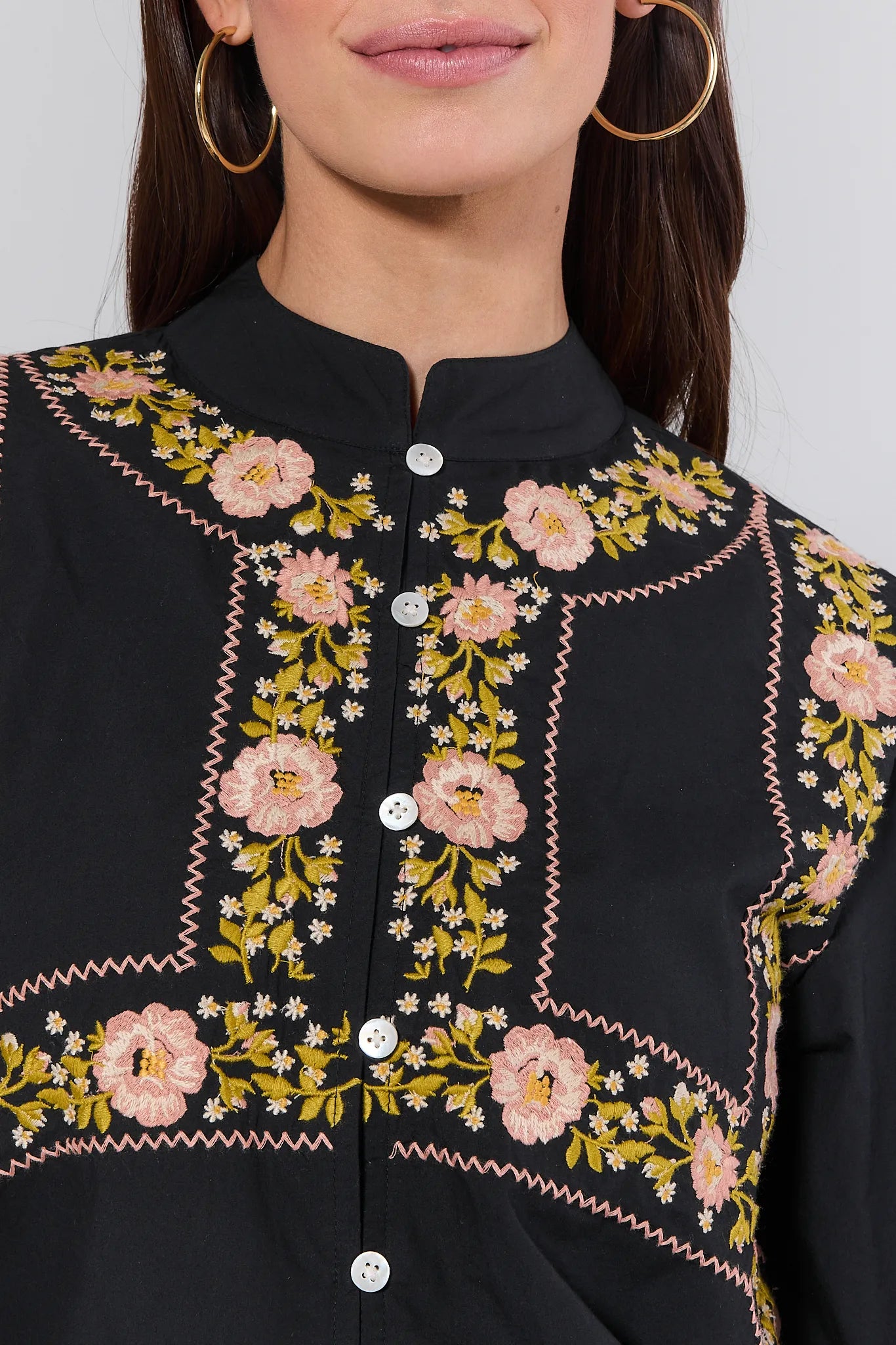 Close-up of a black Selma Top with floral embroidery on a plain background