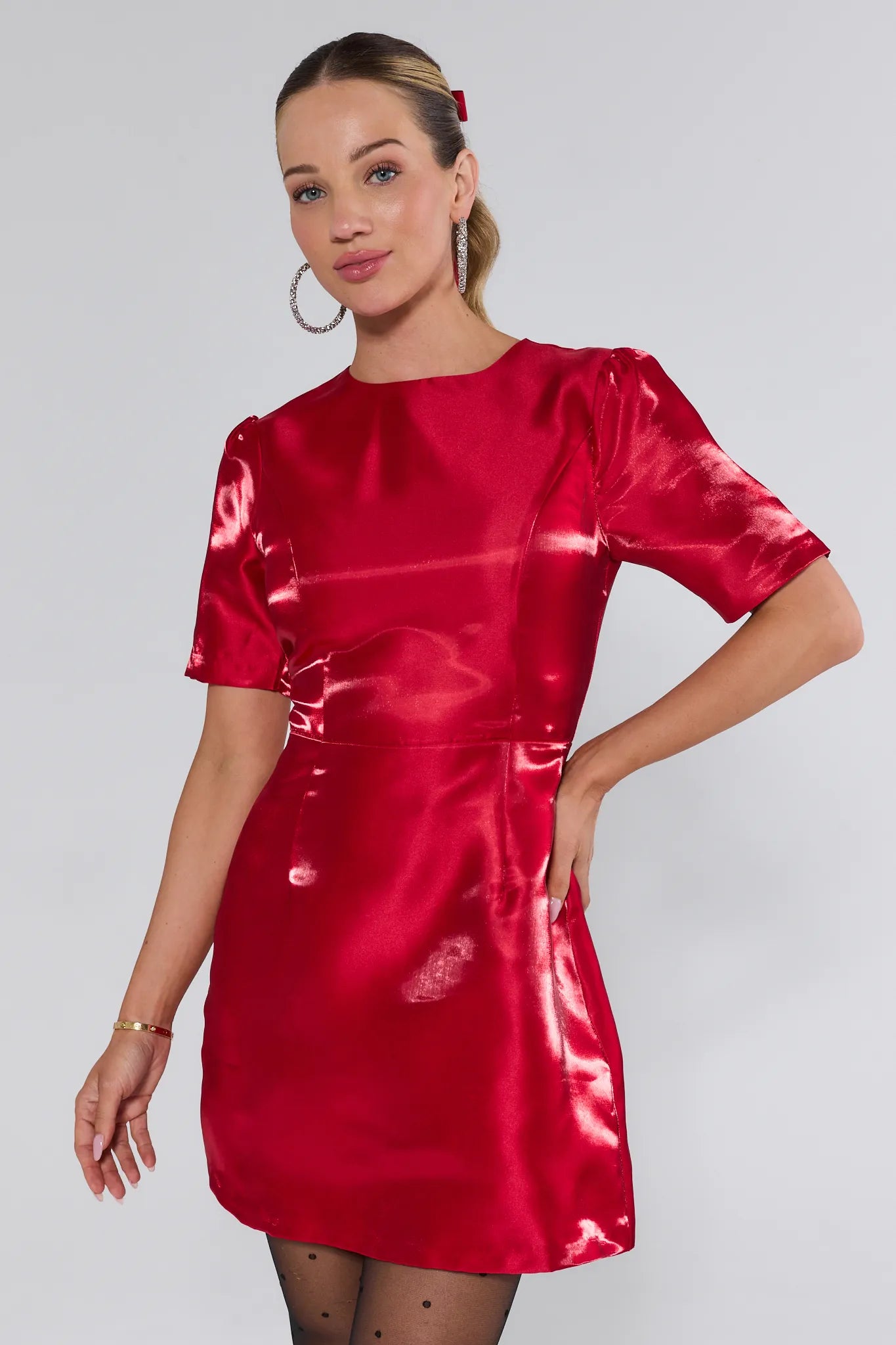 Woman wearing a red satin dress against a plain background