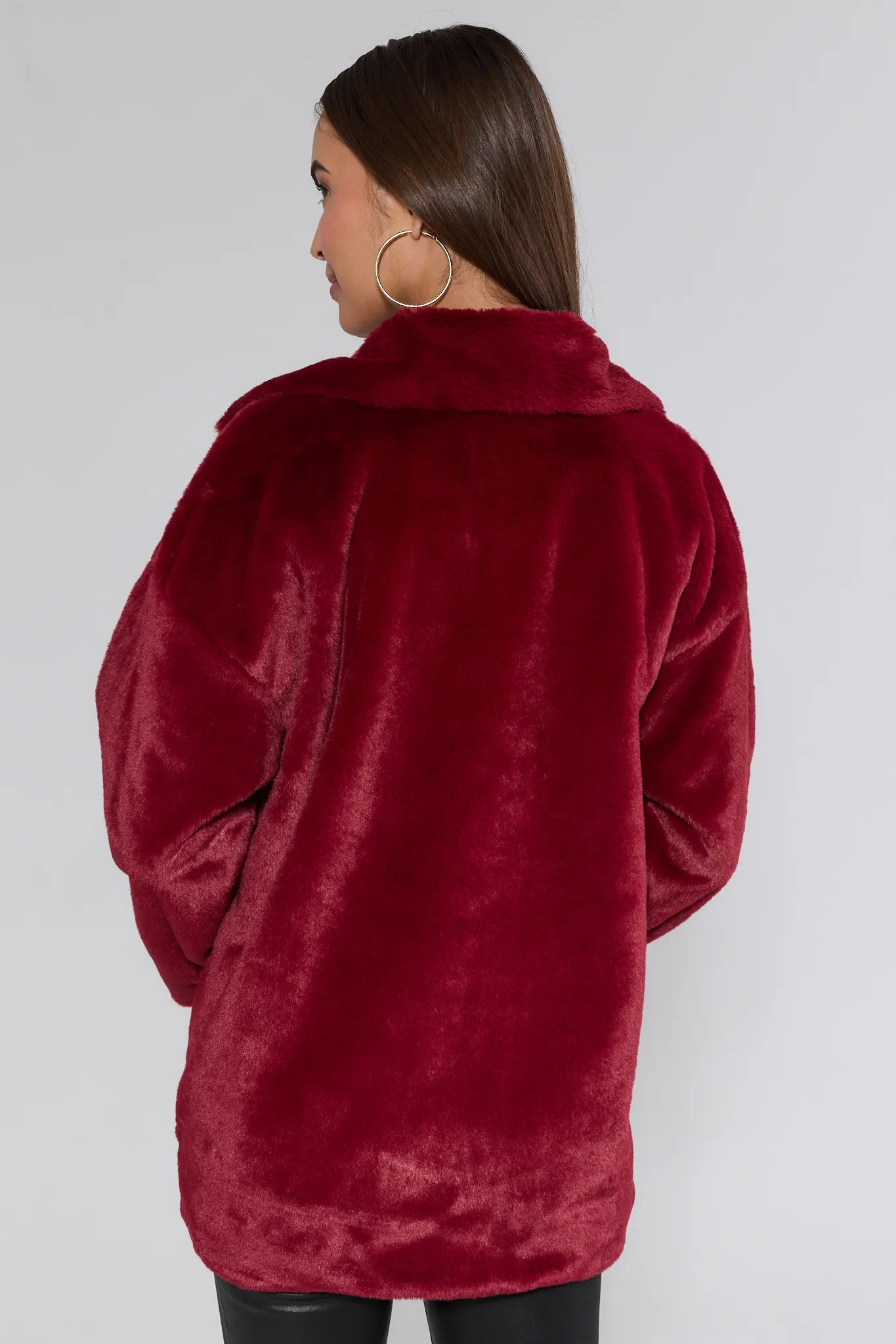 Person wearing a burgundy faux fur coat against a white background