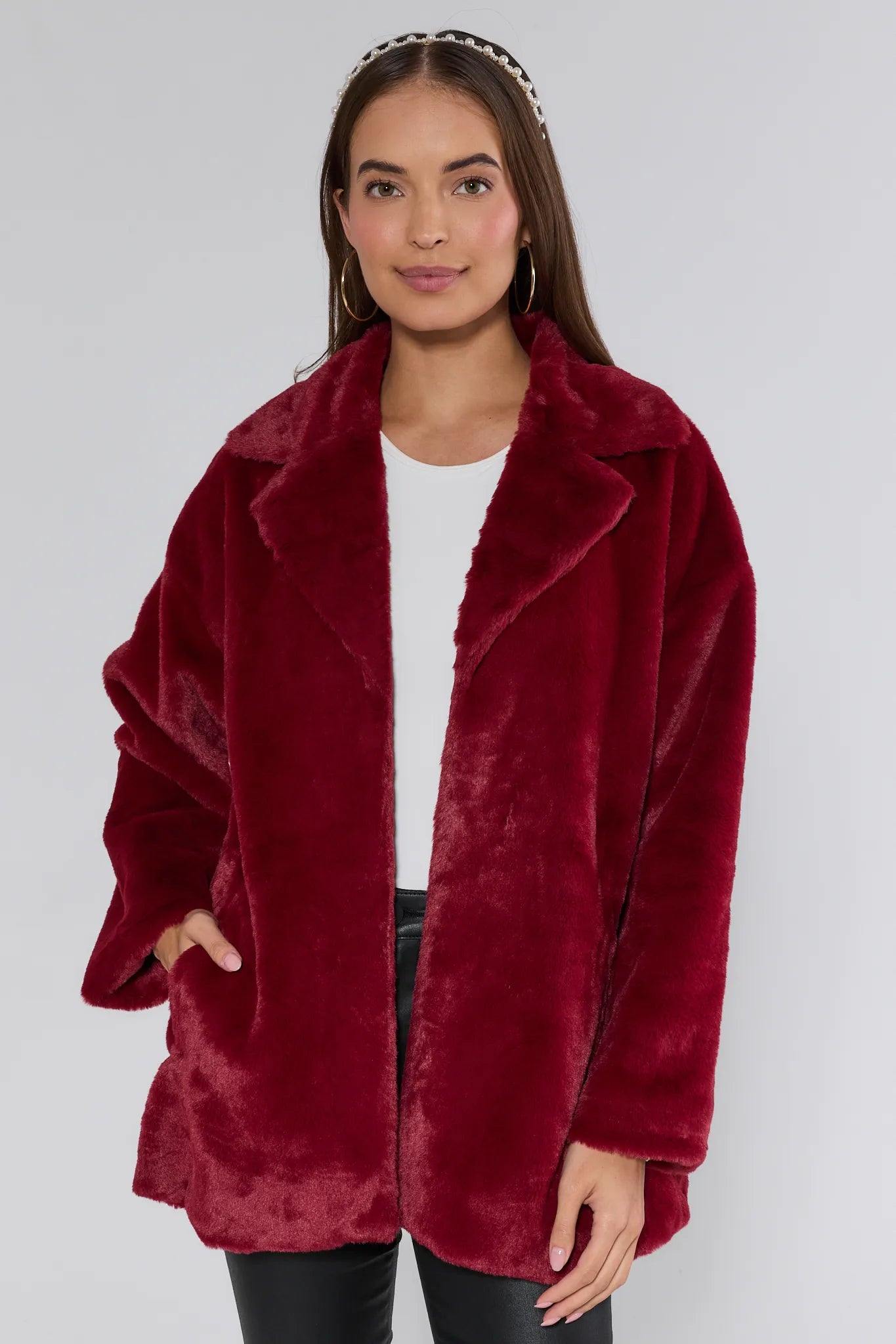 Woman wearing a red faux fur coat against a plain background