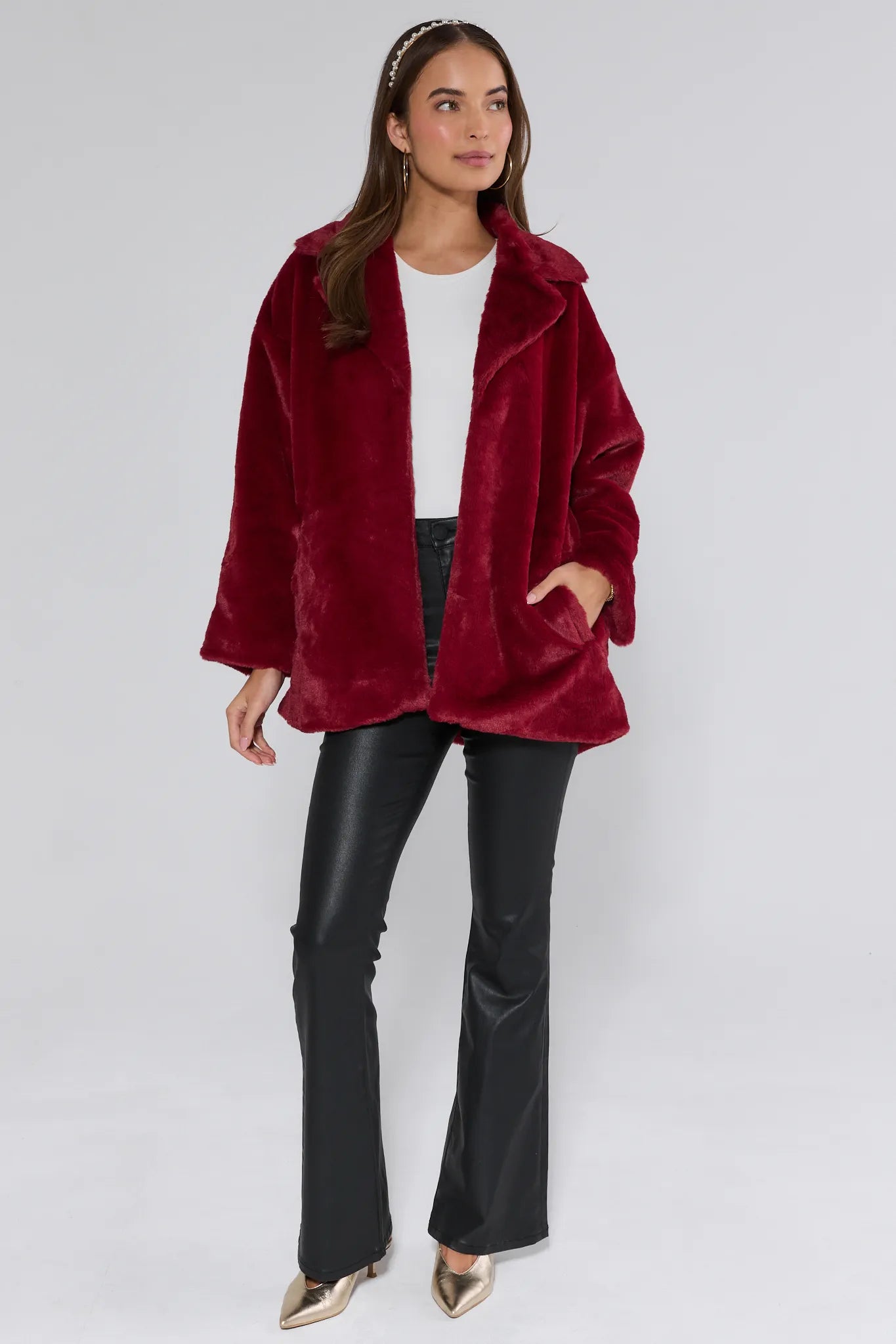 Woman wearing a red coat, white shirt, and black pants on a white background