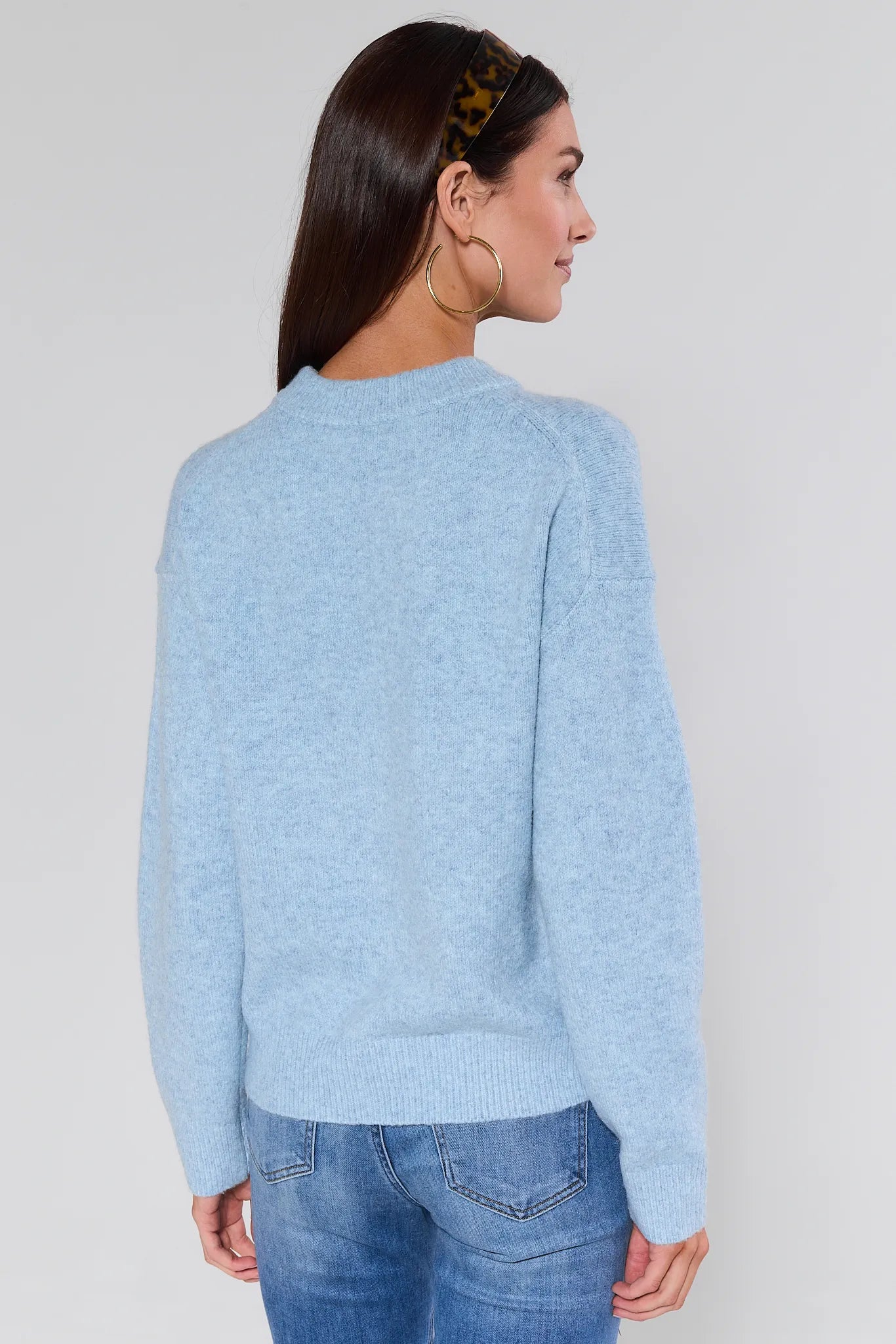 Woman wearing a Natalie Sweater and jeans against a plain background