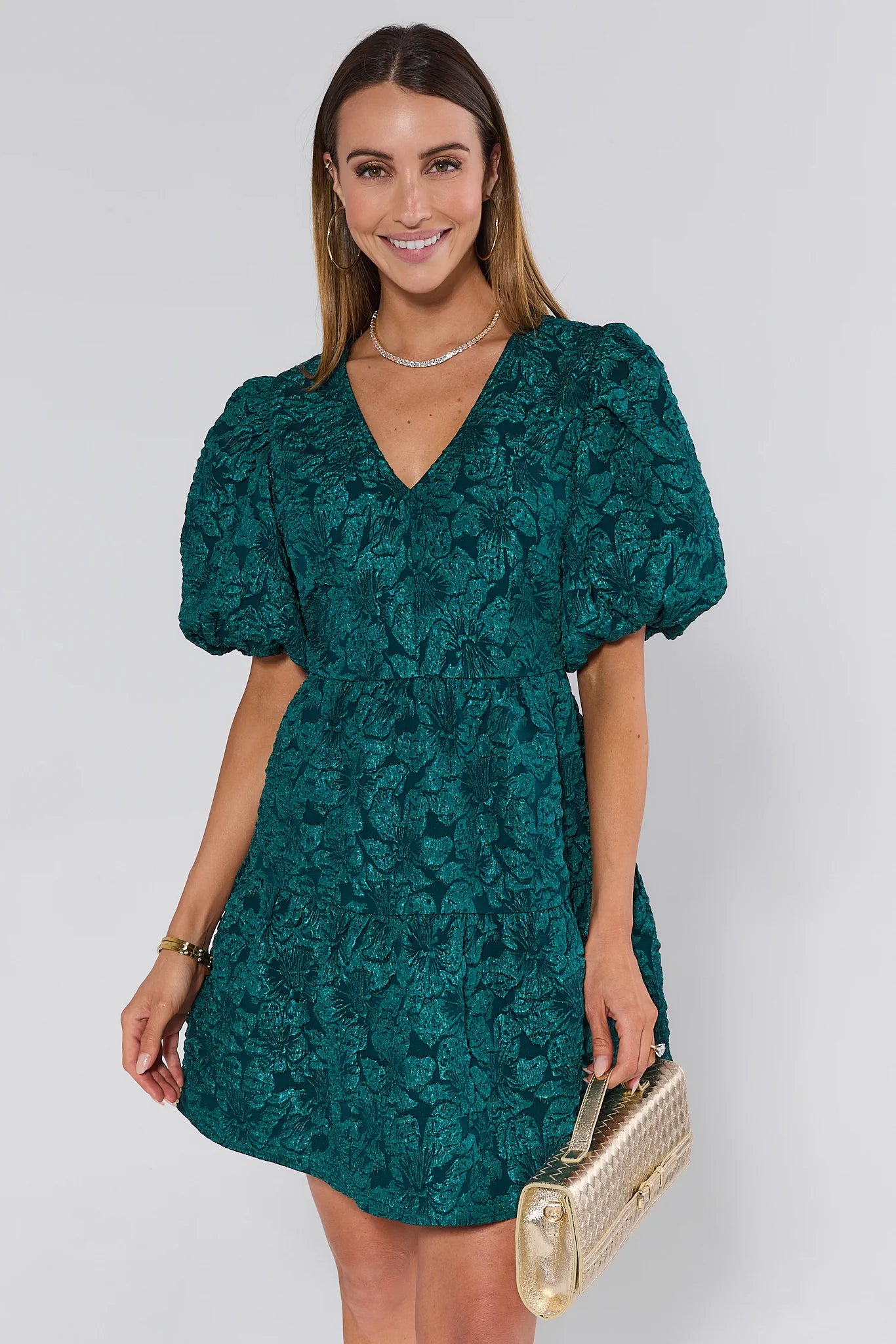 Woman wearing a green floral dress against a white background