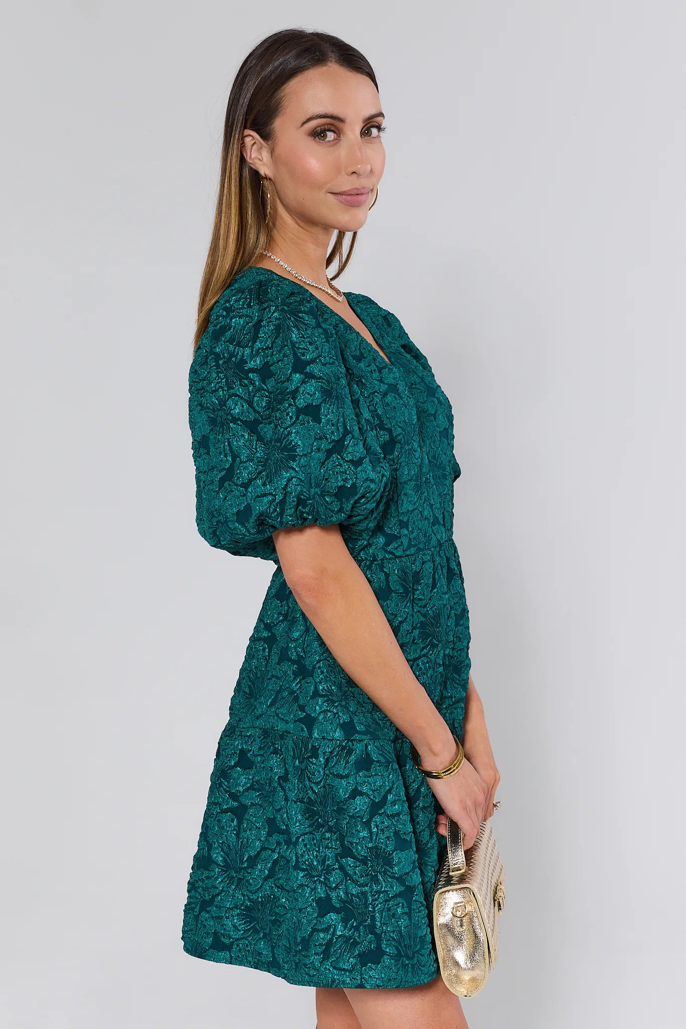 Woman wearing a teal floral dress against a white background