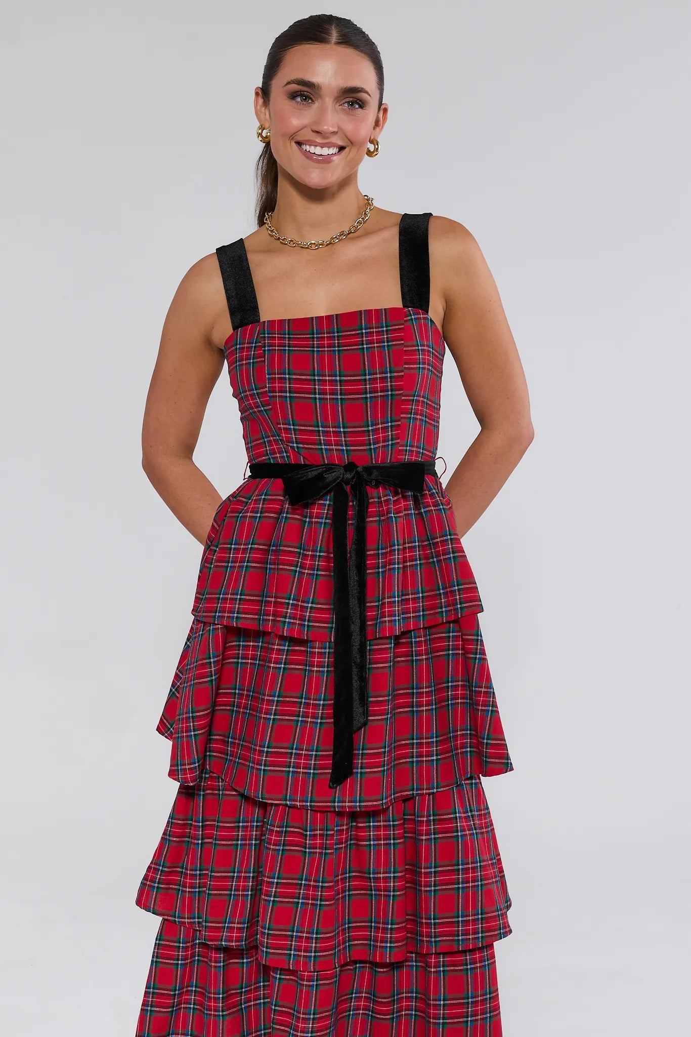 Woman wearing a red plaid catalina dress with black straps on a white background
