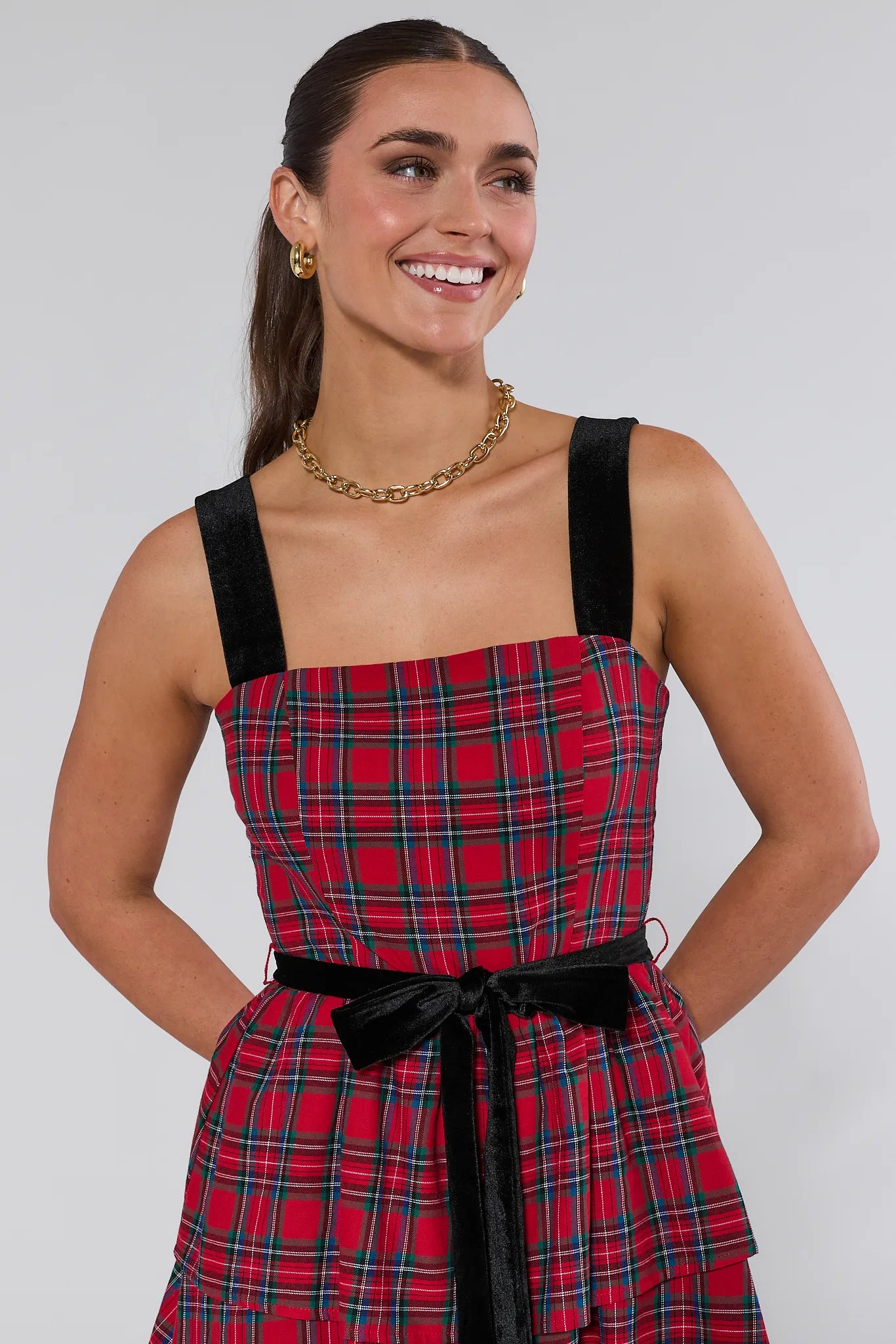 Woman wearing a red plaid catalina dress with black straps on a white background