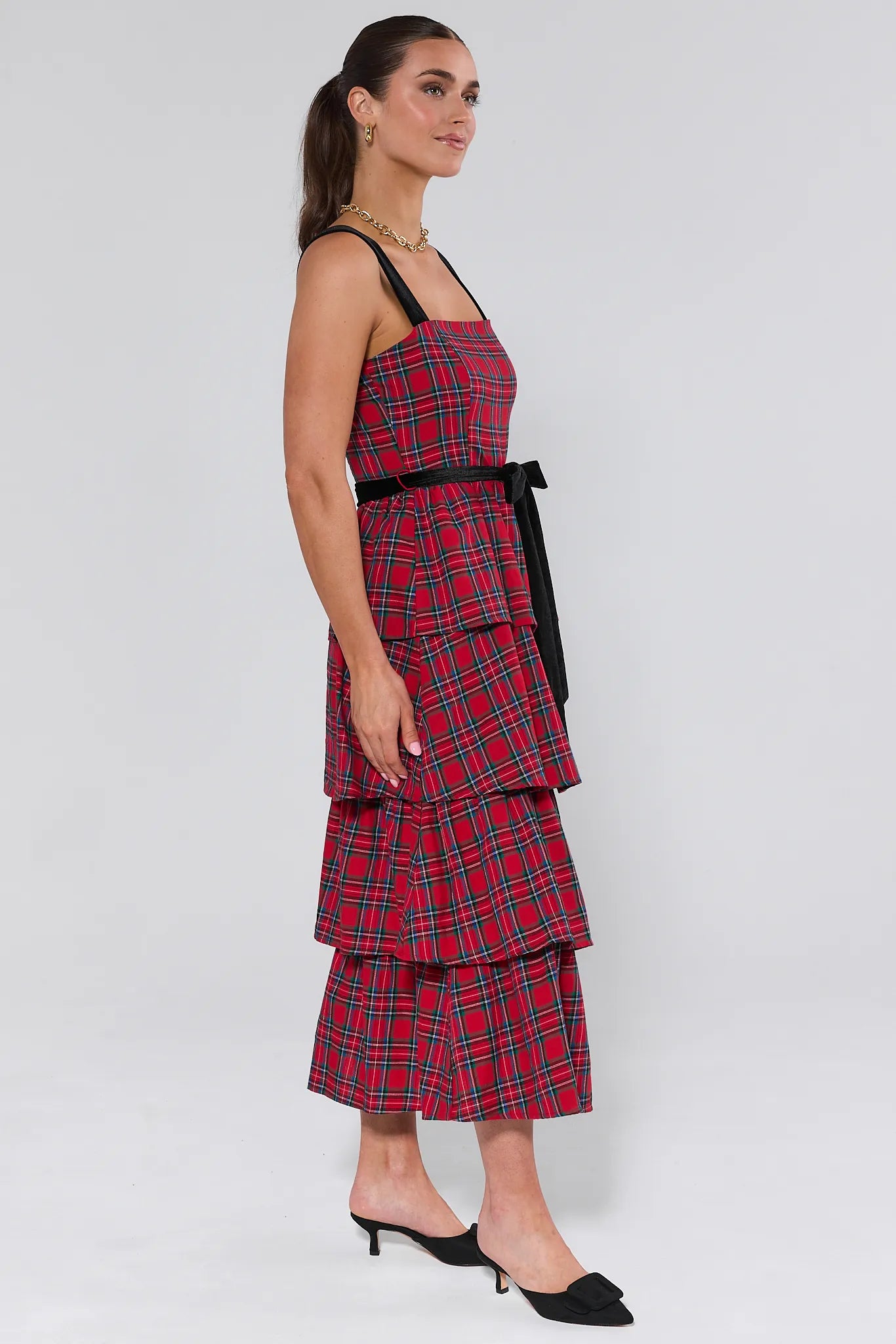 Woman wearing a red plaid catalina dress with black straps on a white background