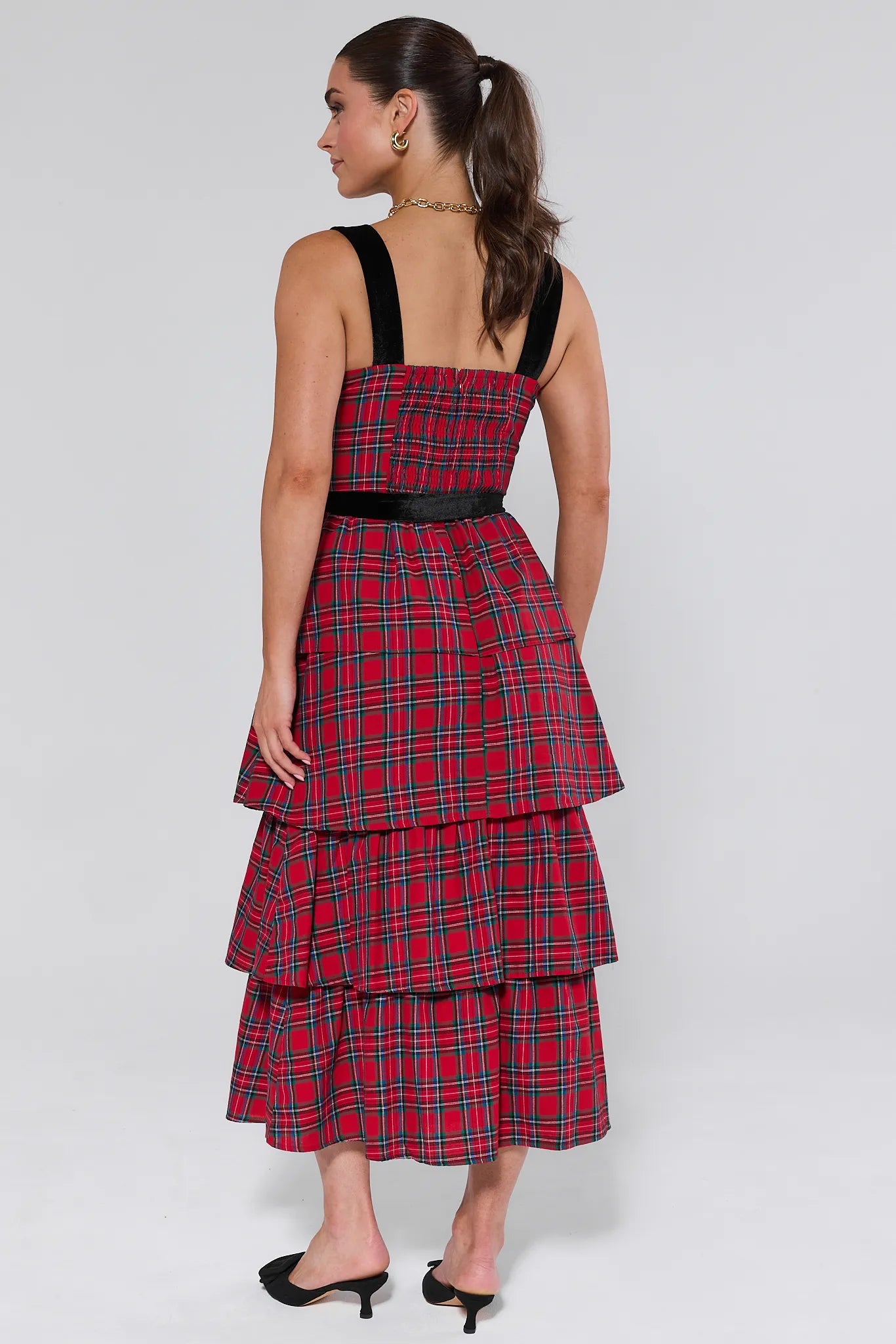 Woman wearing a red plaid catalina dress with black straps on a white background