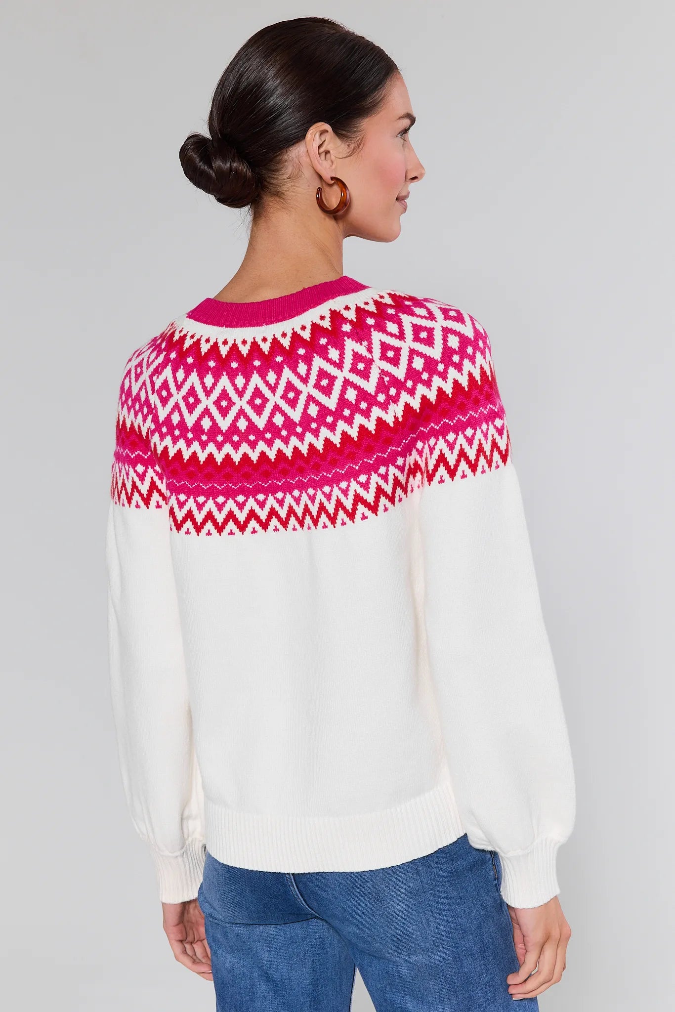 Woman wearing a Patricia White Fair Isle Sweater and blue jeans on a gray background