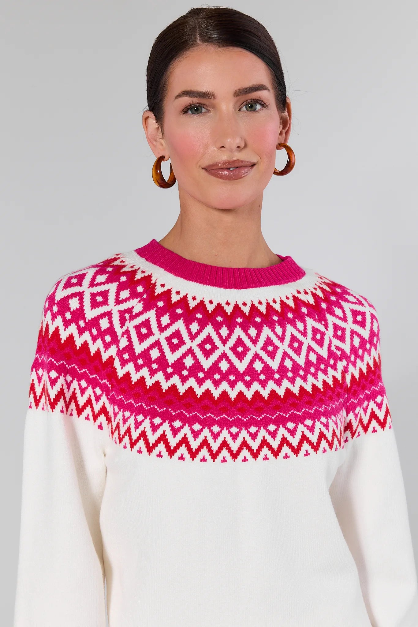 Woman wearing a Patricia White Fair Isle Sweater and blue jeans on a gray background