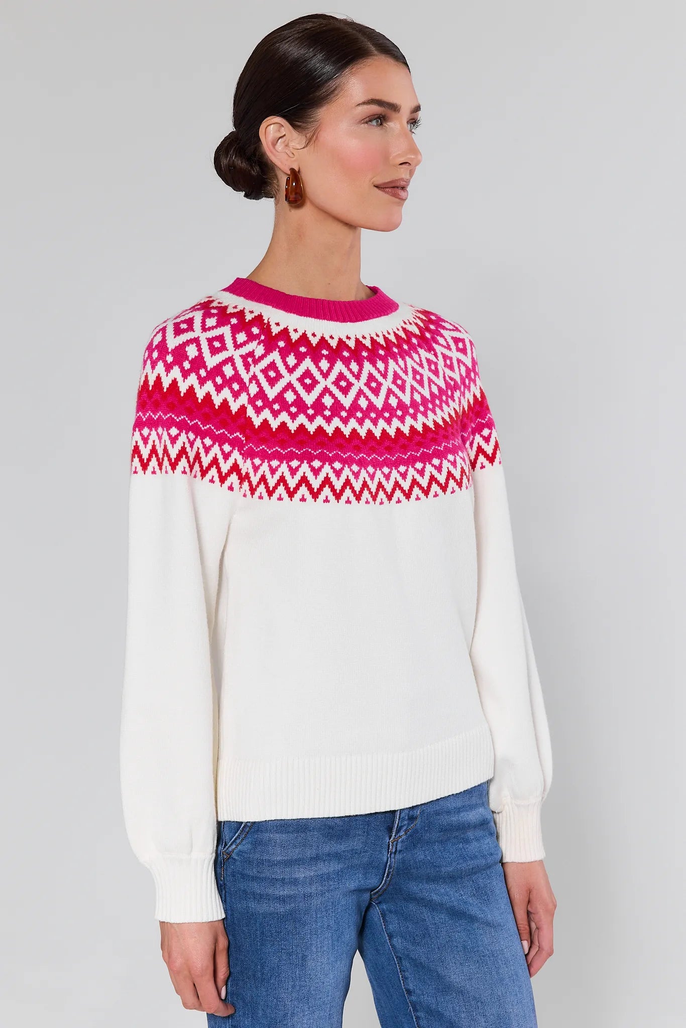 Woman wearing a Patricia White Fair Isle Sweater and blue jeans on a gray background