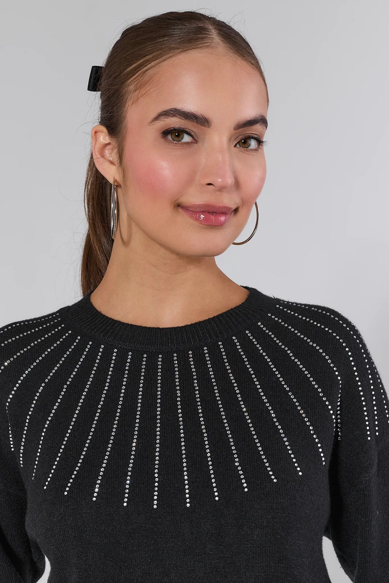 Woman wearing a Sondra Black Embellished Sweater with decorative elements and blue jeans on a white background