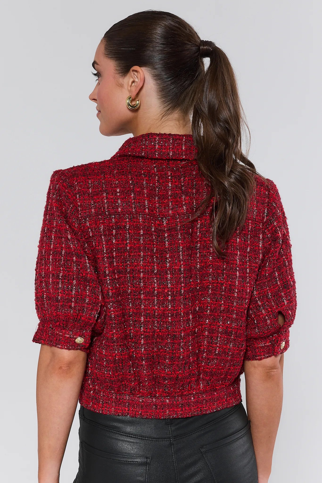 Woman wearing a red tweed jacket on a plain background