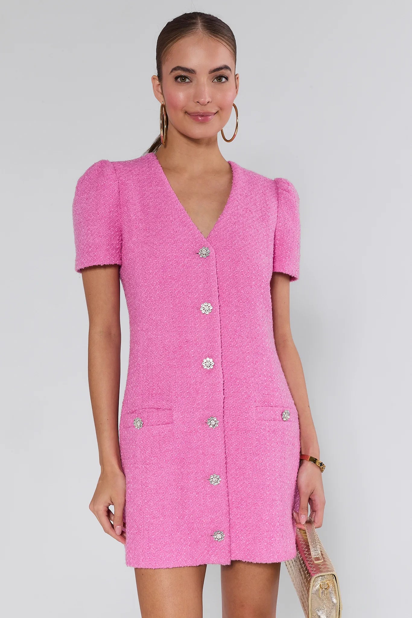 Woman wearing a pink missy dress with buttons on a white background