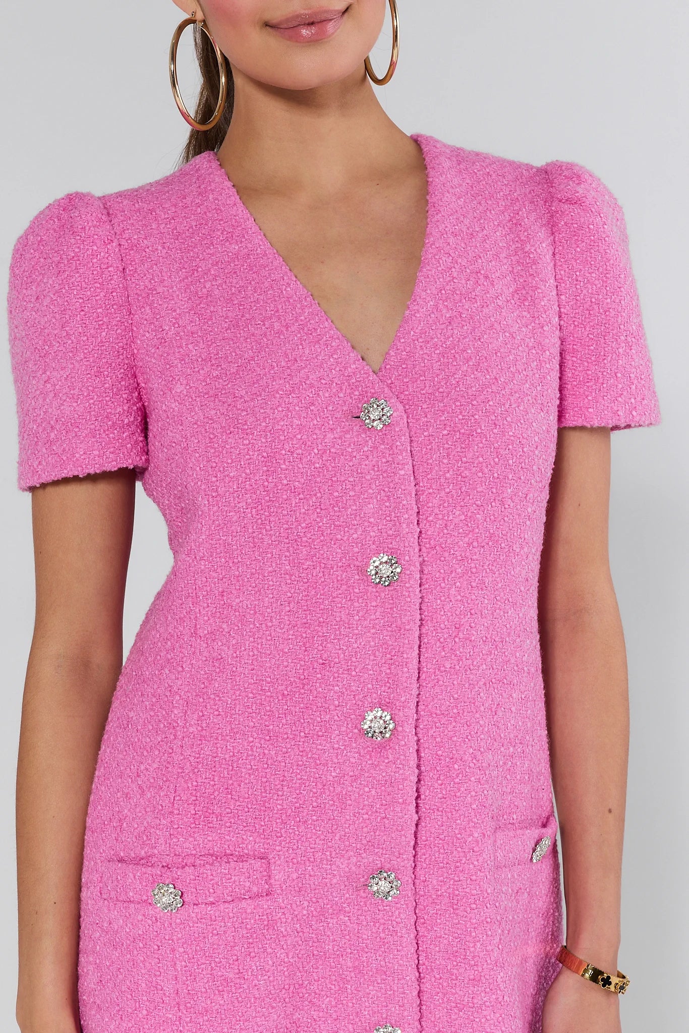 Woman wearing a pink missy dress with buttons on a white background