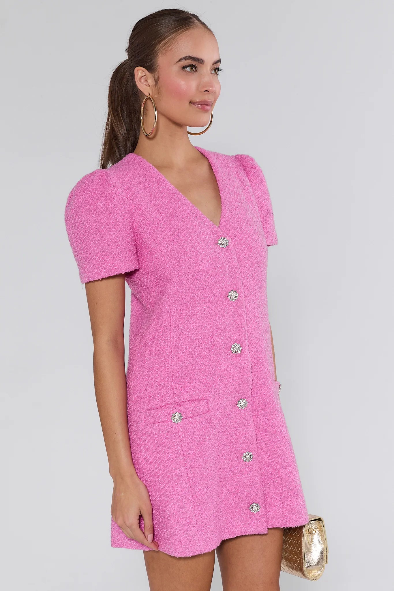 Woman wearing a pink missy dress with buttons on a white background