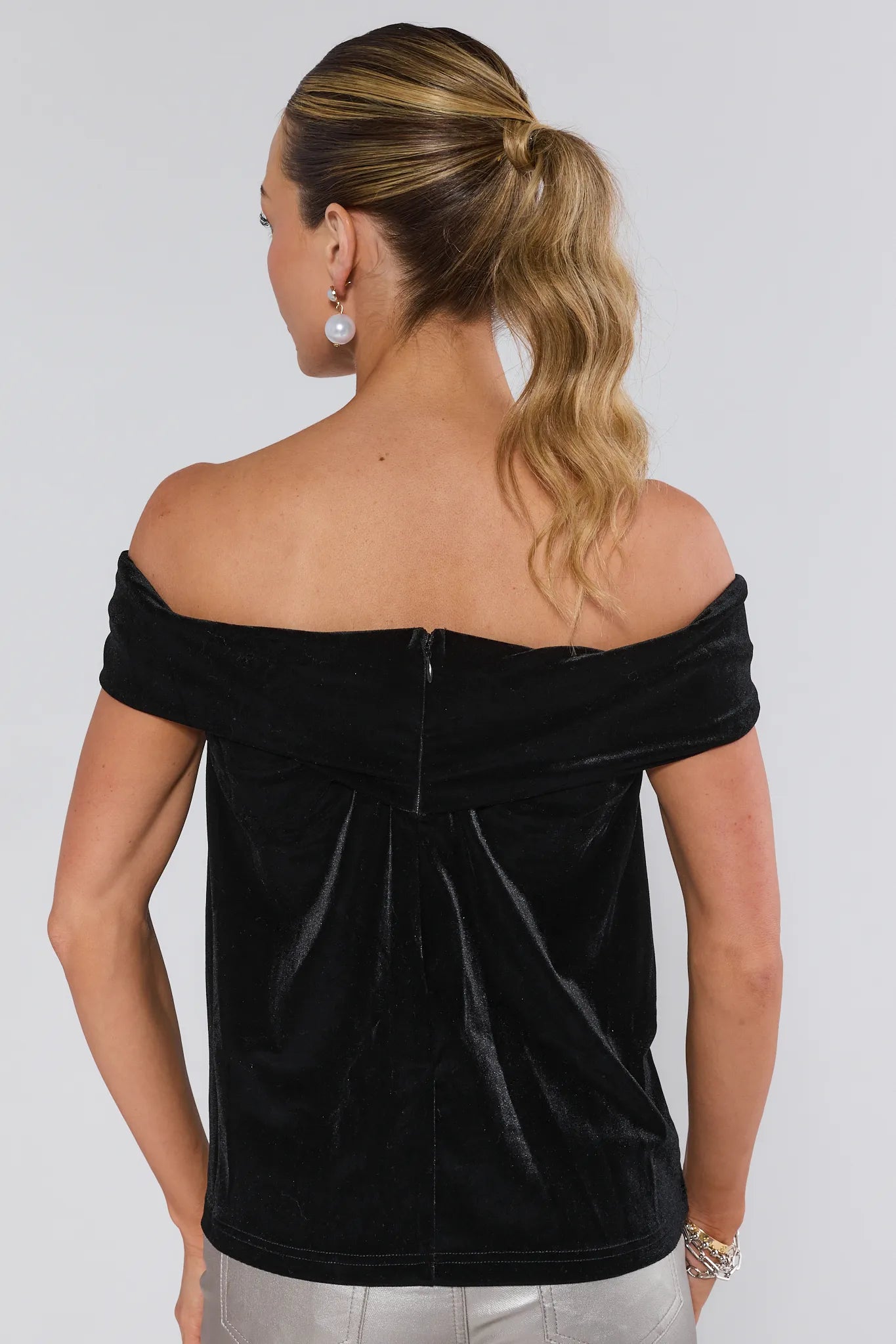 Woman wearing a black off-shoulder top against a plain background