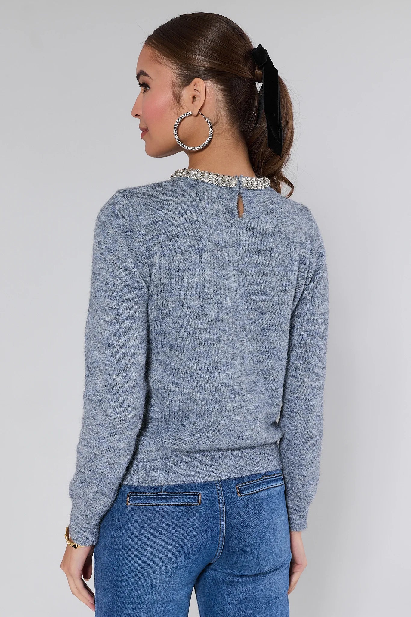 Woman wearing a Blythe sweater with a decorative neckline against a plain background