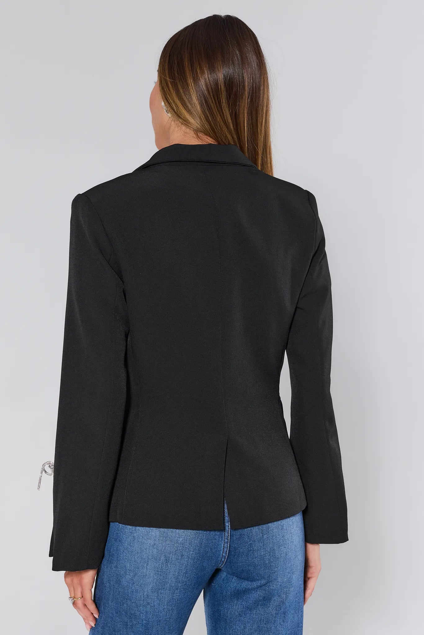 Person wearing a Drew Black Bow Blazer and blue jeans on a white background