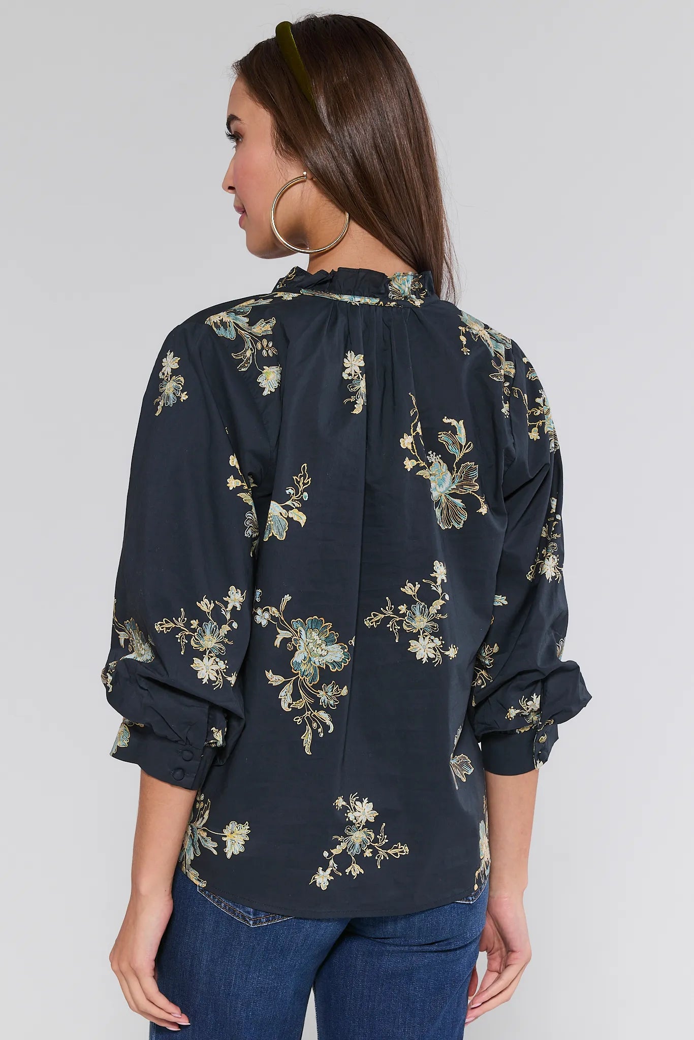 Woman wearing a dark floral Michelle Top against a plain background