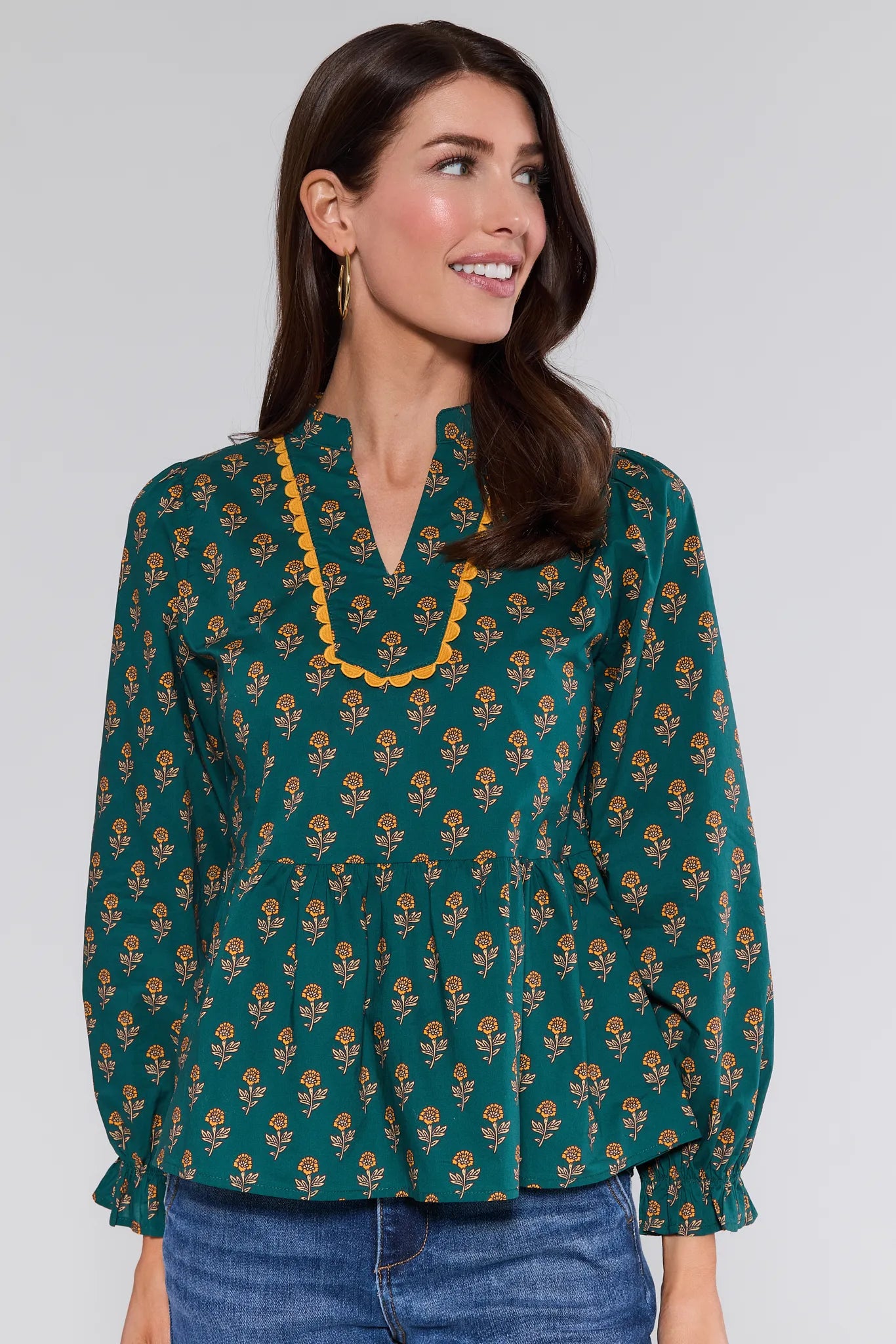 Woman wearing a green patterned Fallon Top with yellow trim on a plain background
