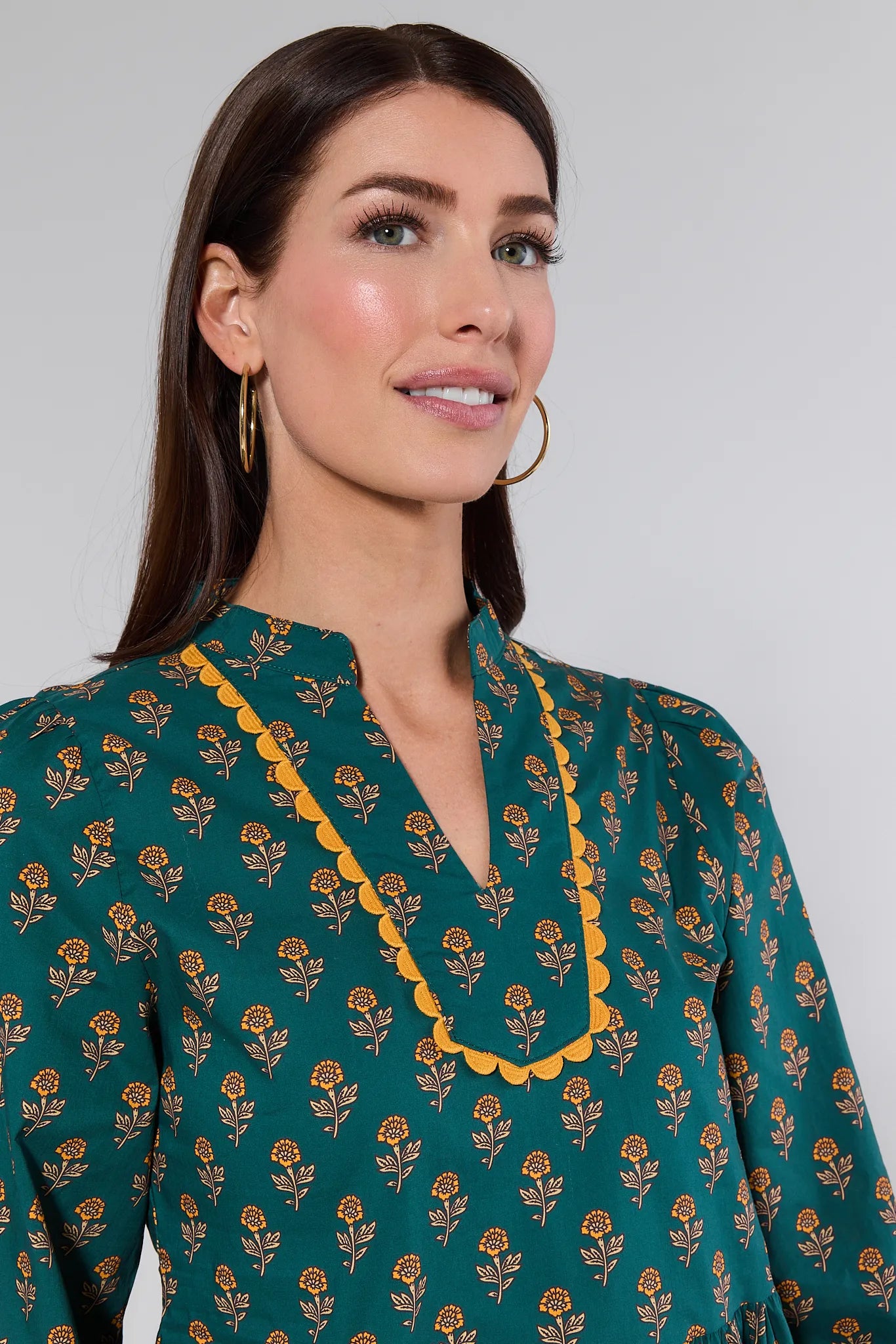 Woman wearing a Fallon Top with floral pattern and yellow trim against a gray background