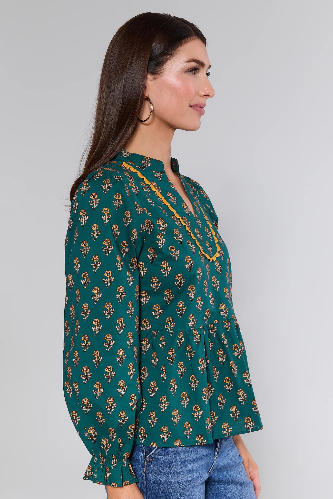 Woman wearing a green patterned Fallon Top with a plain background