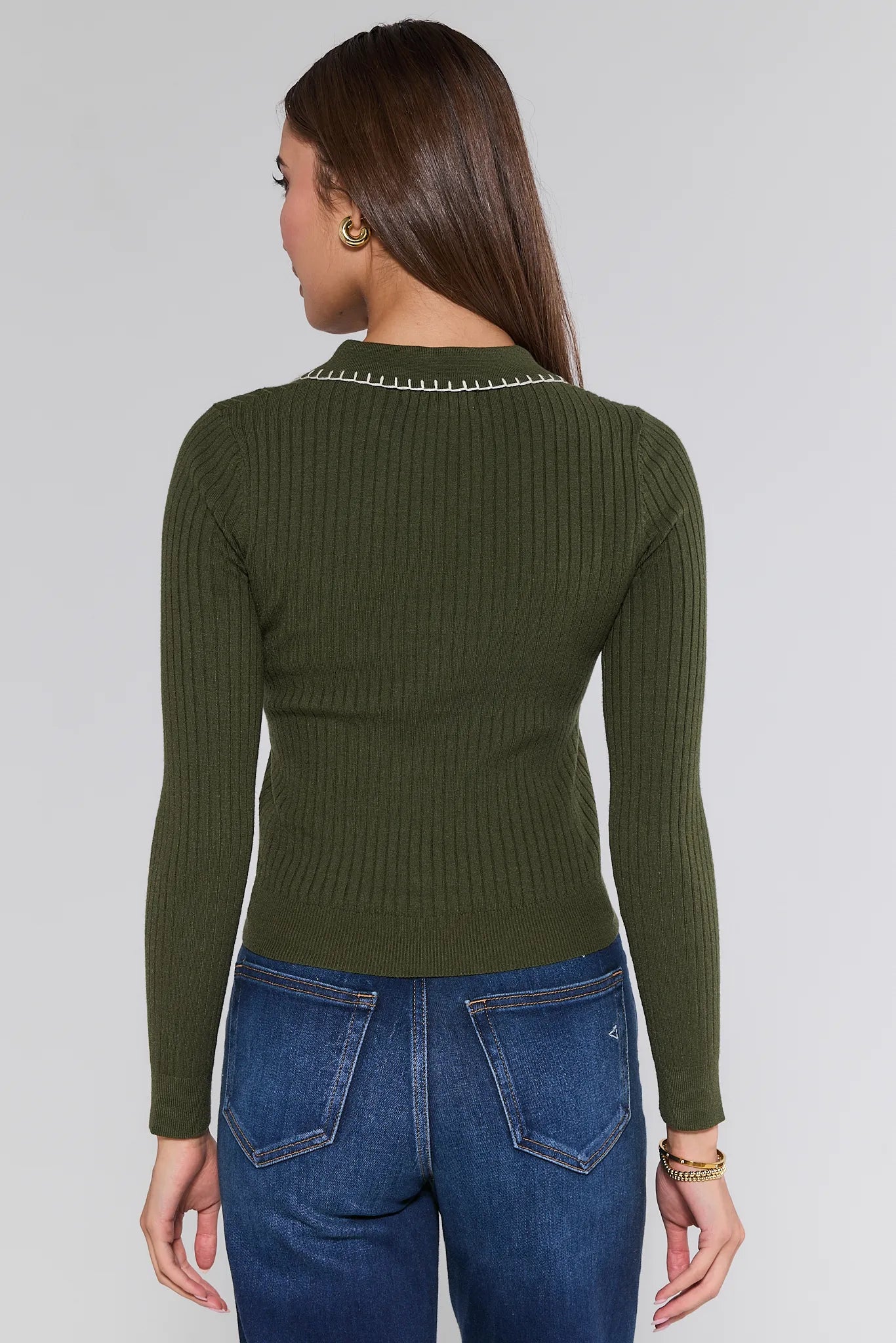 Person wearing an olive green ribbed Shayla Sweater and blue jeans on a white background