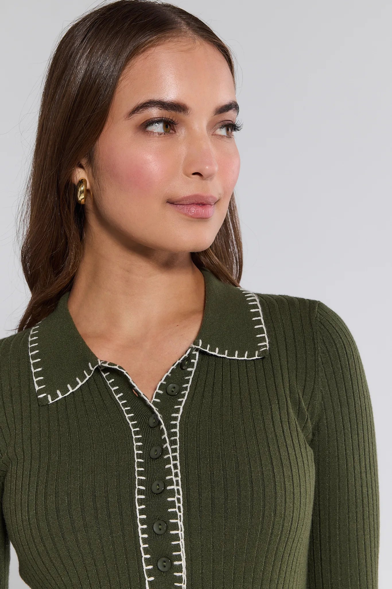 Woman wearing a green ribbed Shayla Sweater with white trim on a plain background
