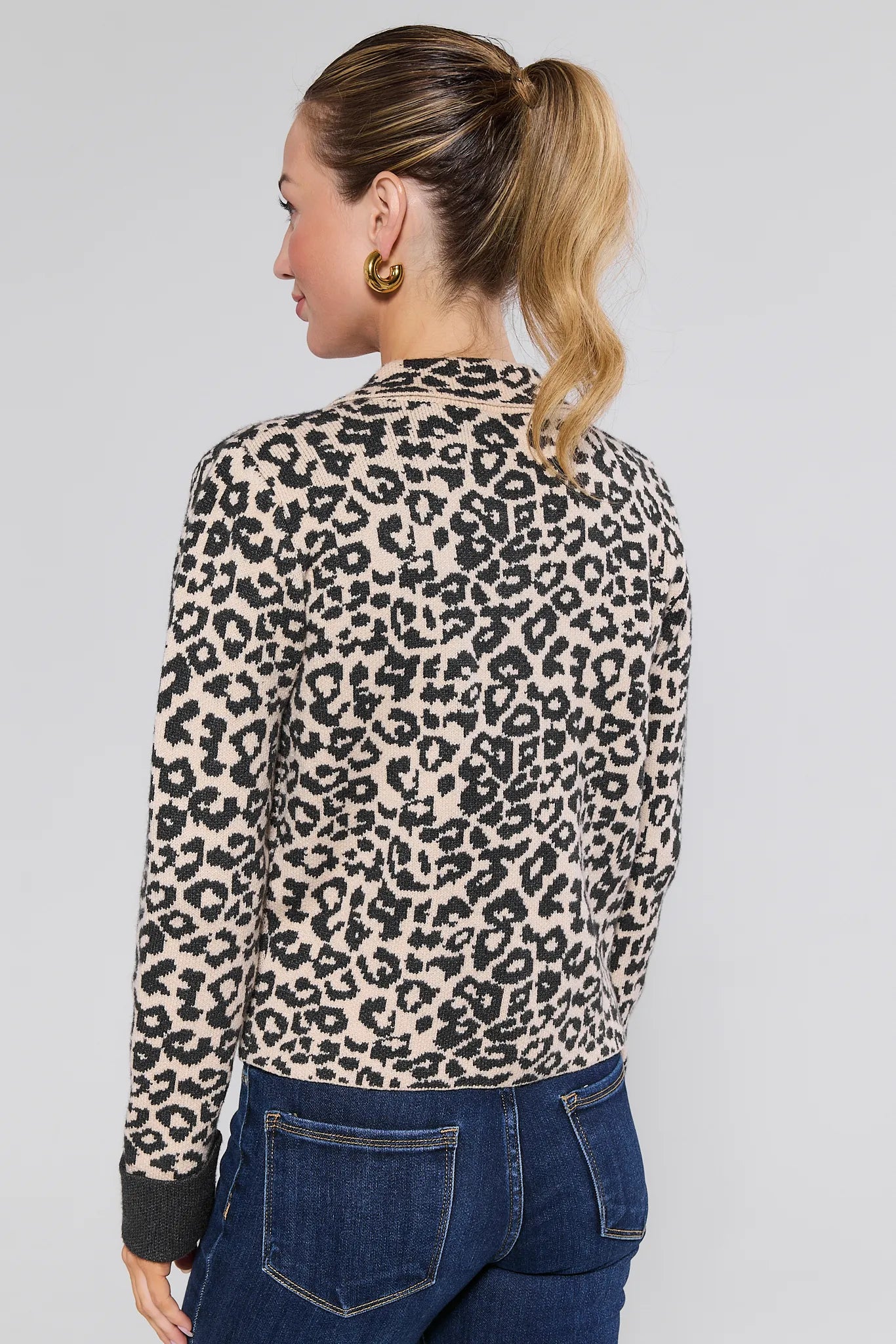 Woman wearing a leopard print Molly Jacket and blue jeans on a plain background