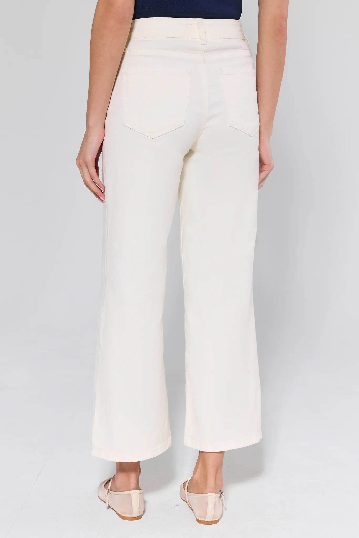 Person wearing white wide-leg pants on a plain background