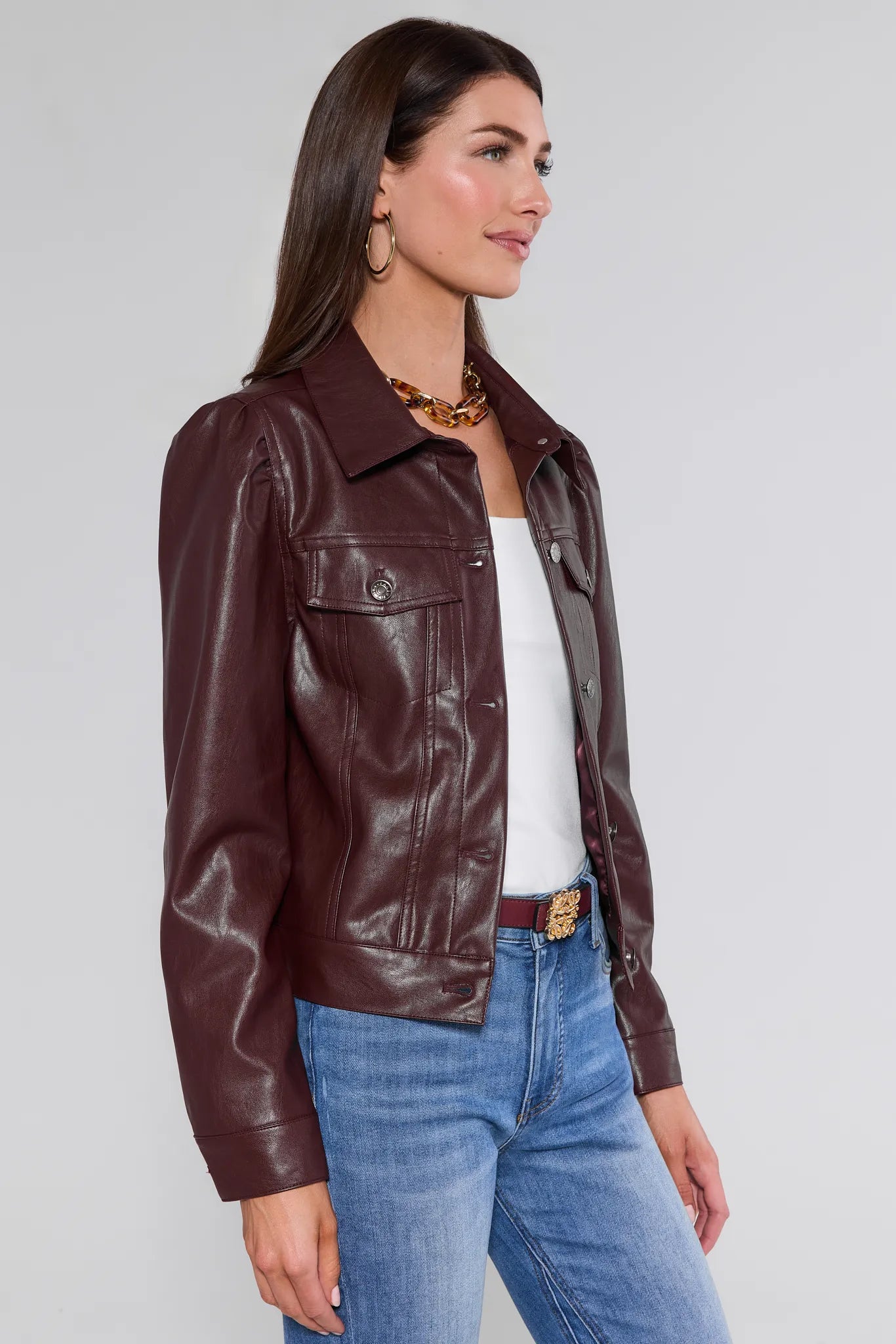 Woman wearing a brown Roxanna Leather Jacket and blue jeans on a plain background