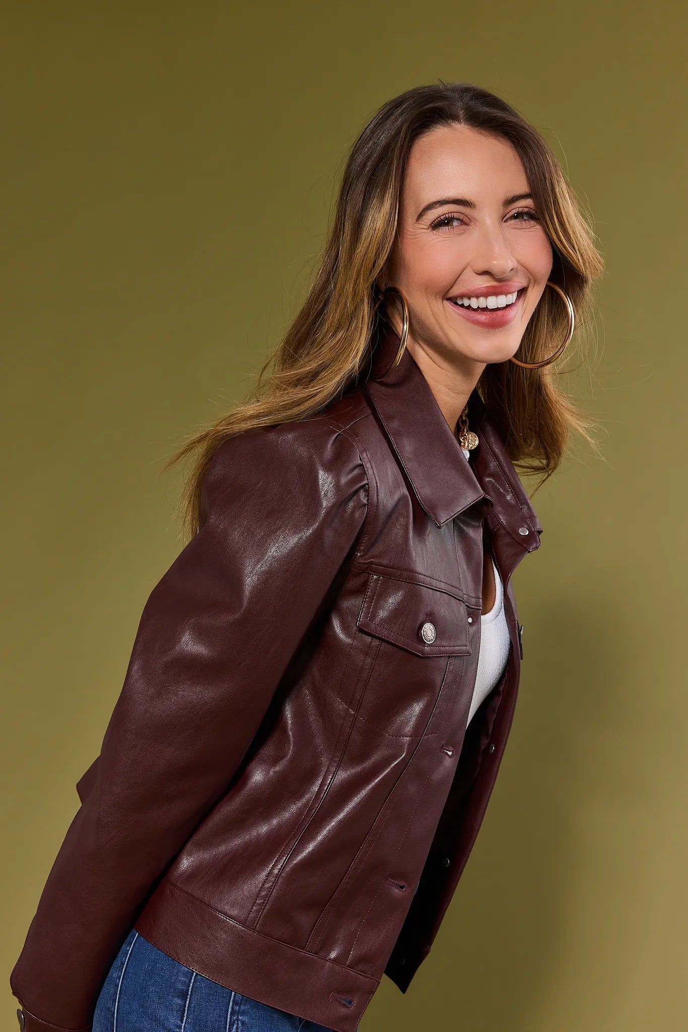Woman wearing a brown Roxanna Leather Jacket against a green background