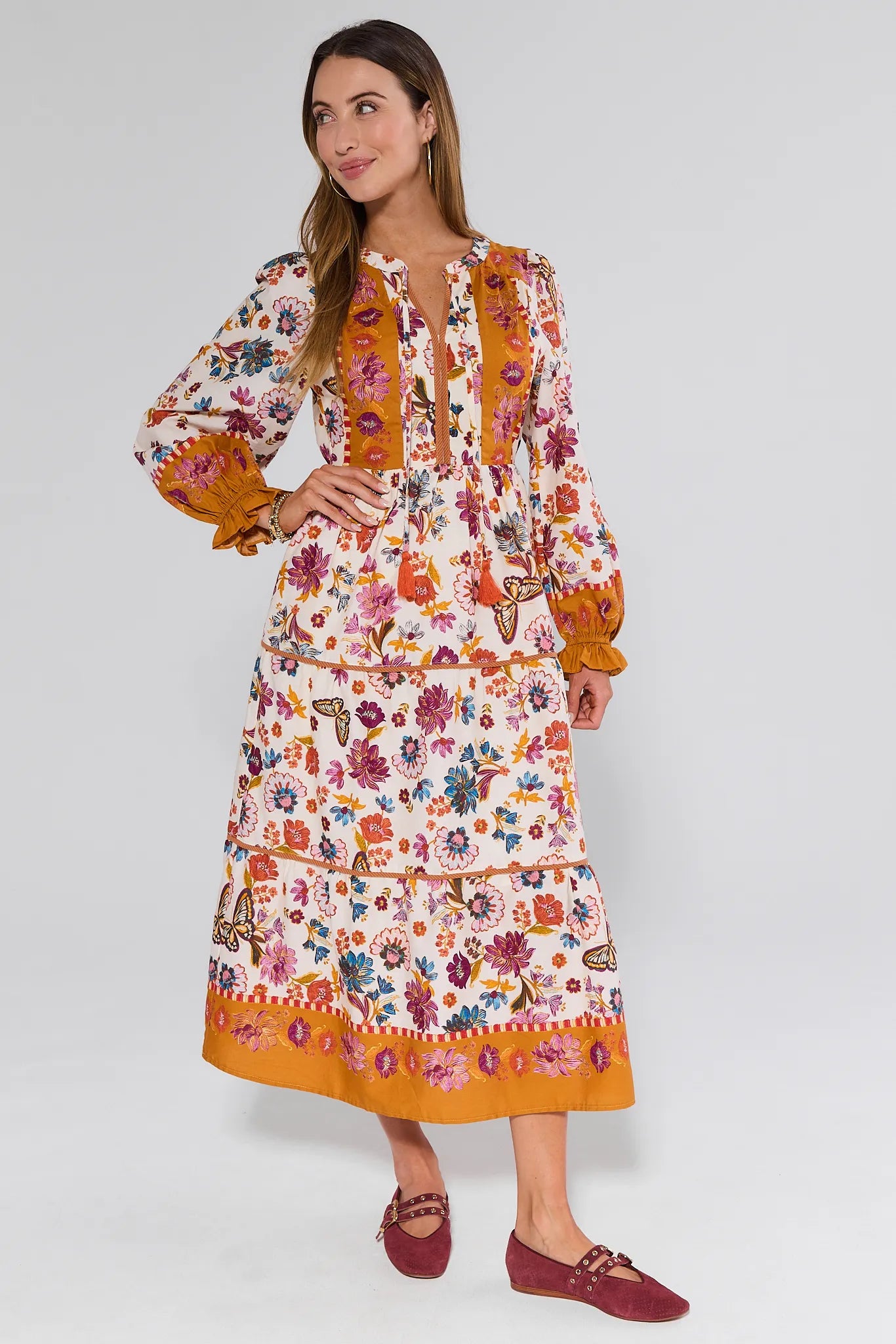 Woman wearing a colorful floral Shiloh Dress with long sleeves on a white background