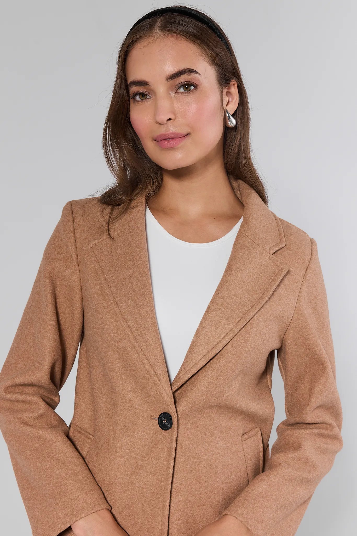 Woman wearing a brown Lauren Coat
over a white shirt on a gray background