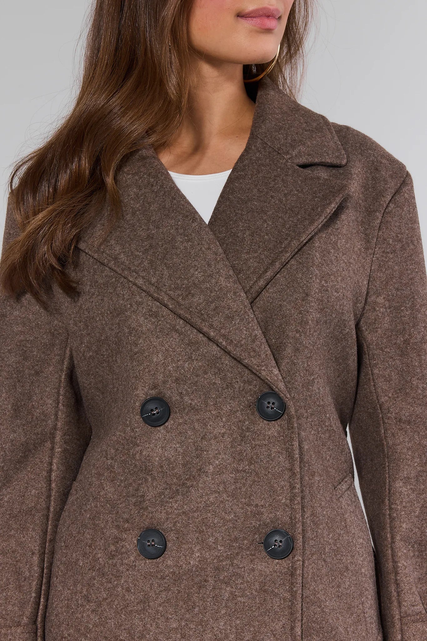 Brown Sadie Coat with black buttons worn by a person on a light gray background