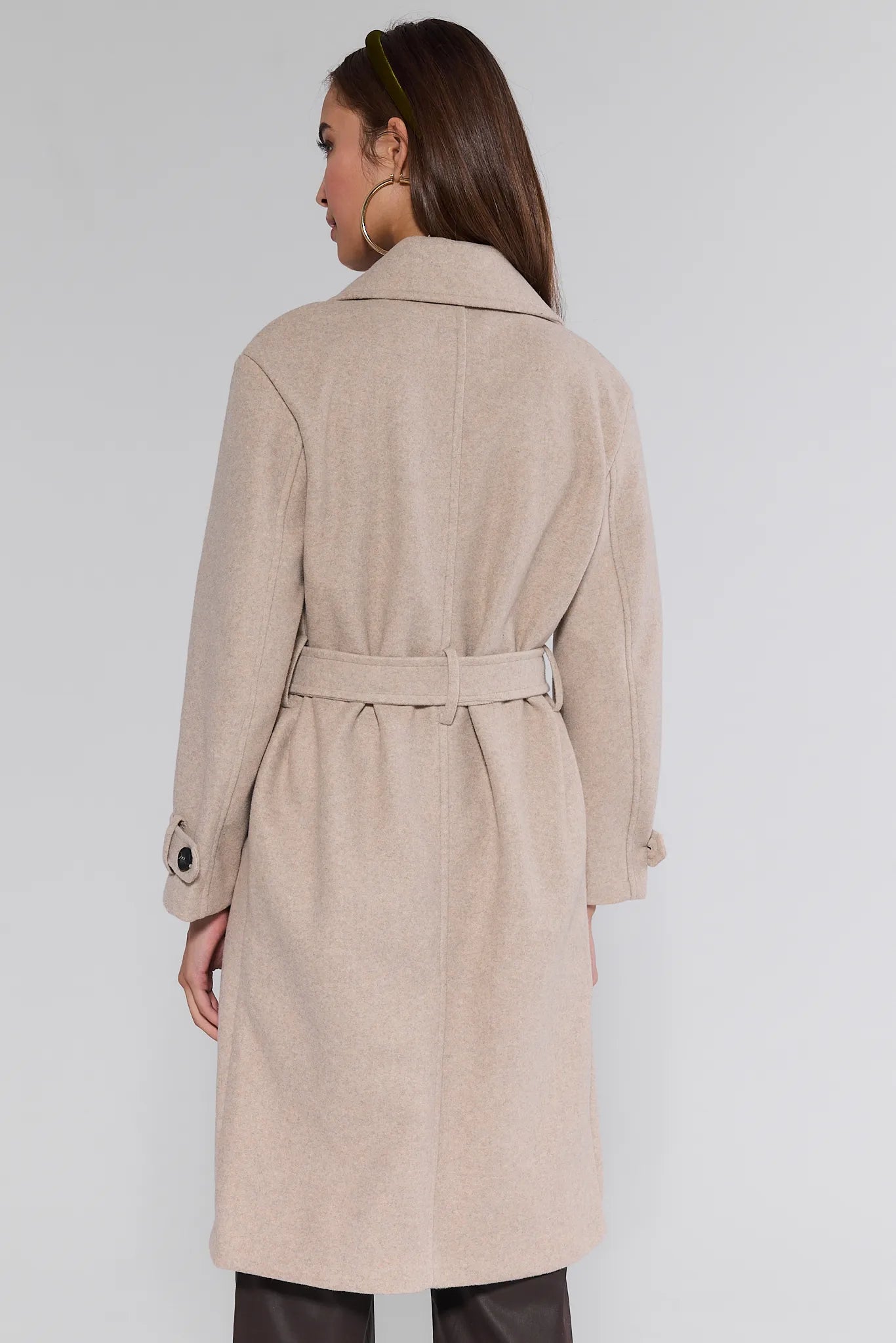 Woman wearing a beige trench Sadie Coat on a plain background