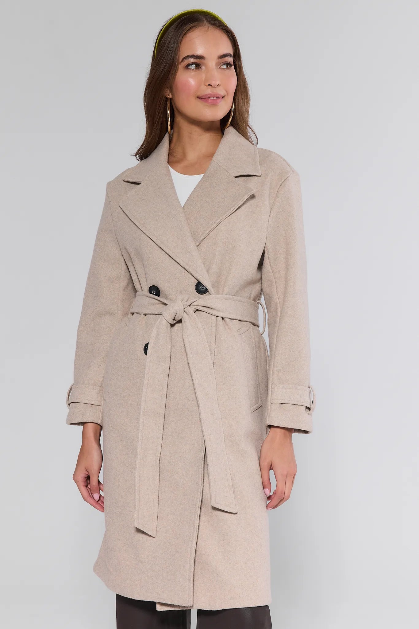 Woman wearing a beige trench Sadie Coat on a white background