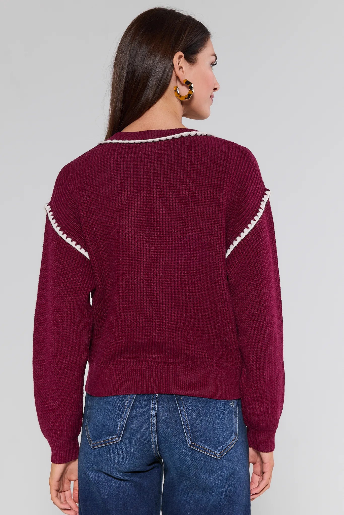 Woman wearing a burgundy Morgan Cardigan with white trim on a plain background