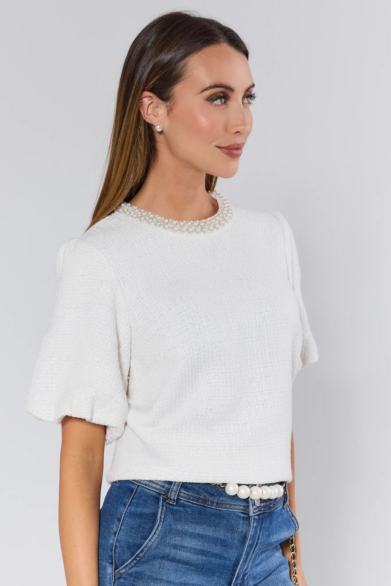 Woman wearing a white Blakely Top with pearl details against a plain