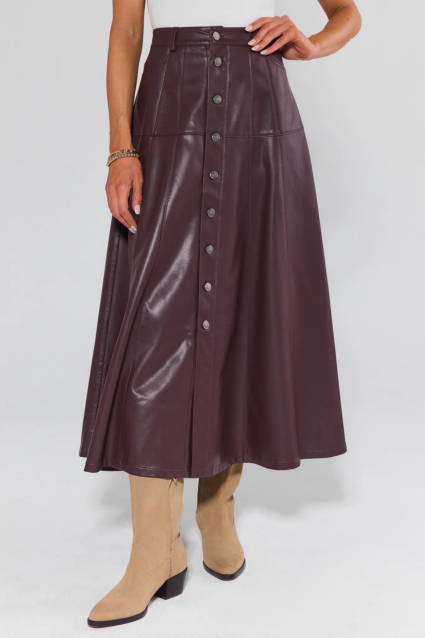 Person wearing a long, dark brown leather Preston Skirt with buttons on a white background