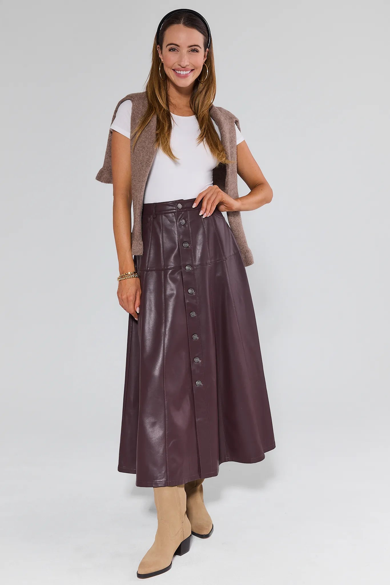 Woman wearing a brown leather Preston Skirt with a plain background