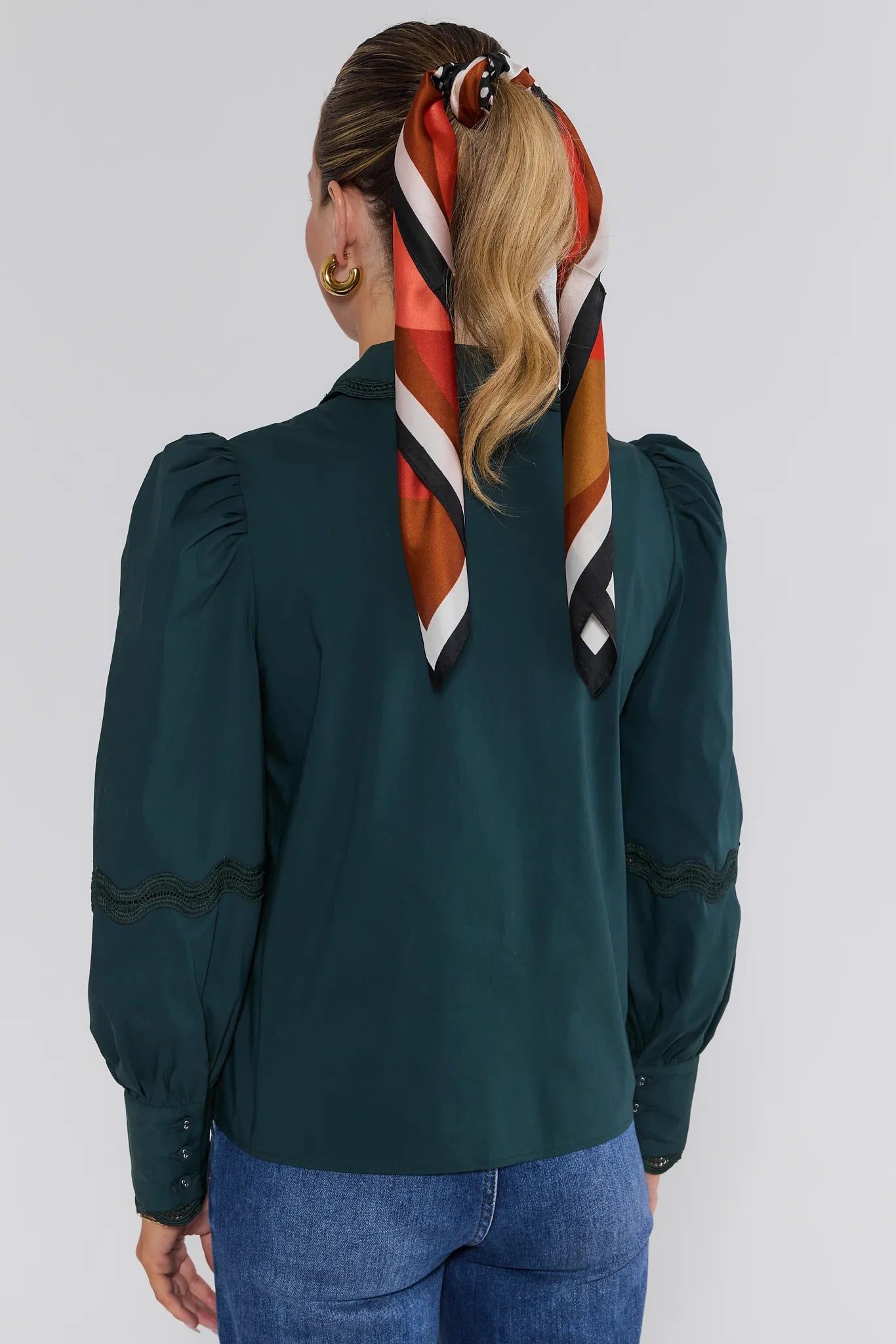 Person wearing a green Ellis Top with a colorful scarf in their hair against a white background