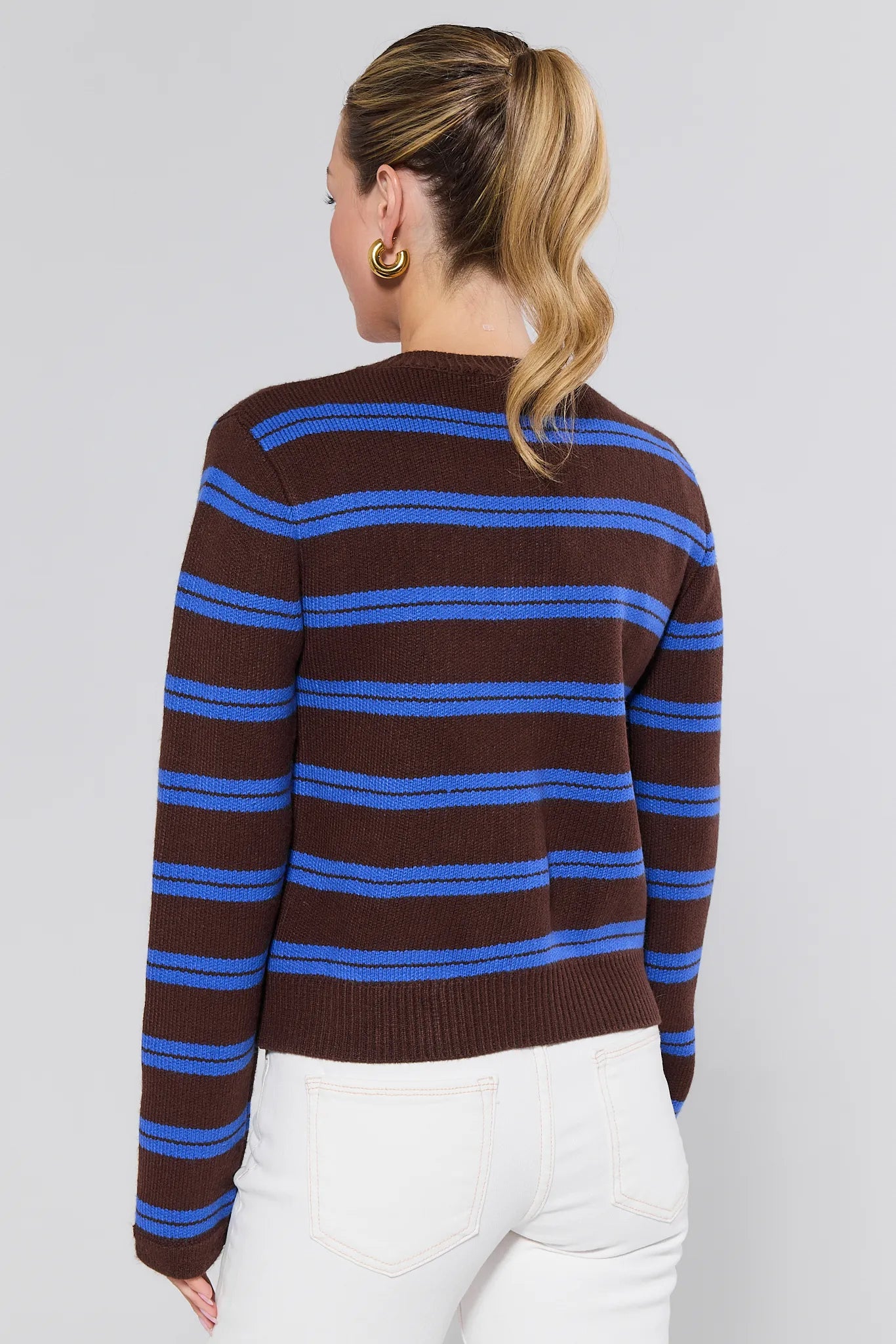 Woman wearing a brown and blue striped Chandler Cardigan against a plain background