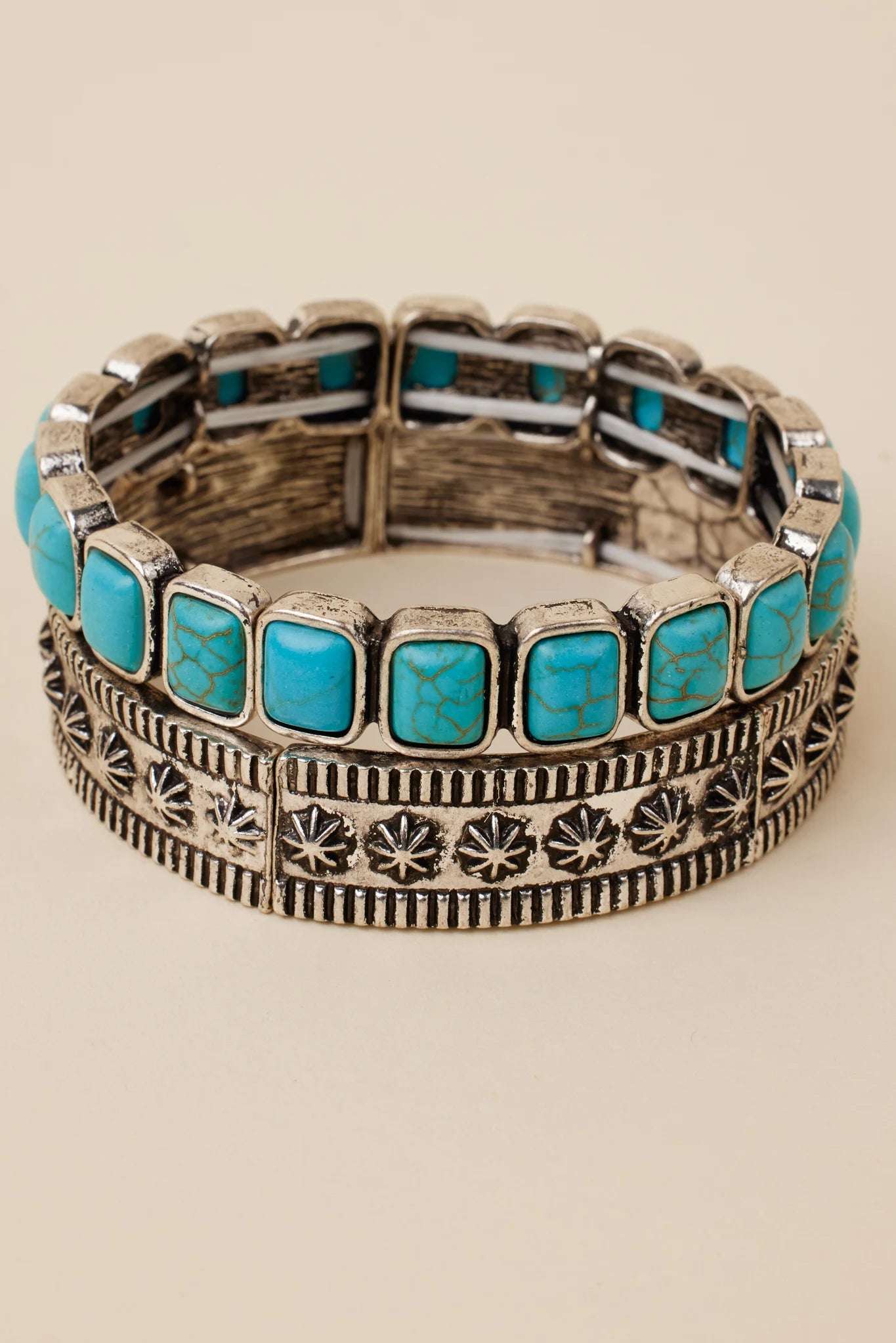 Stack of silver and turquoise bracelets on a beige background