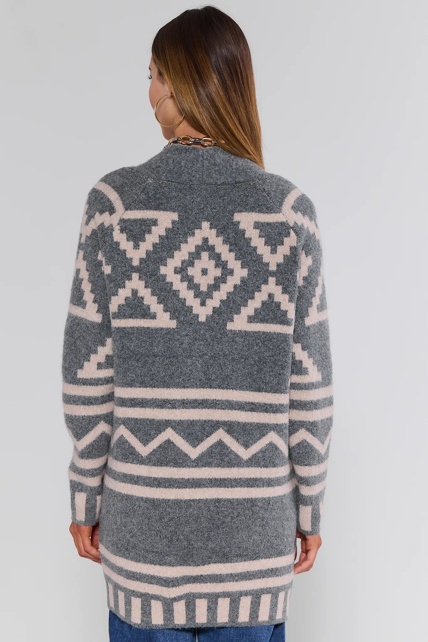 Person wearing a gray Helena Cardigan with a geometric pattern on a white background