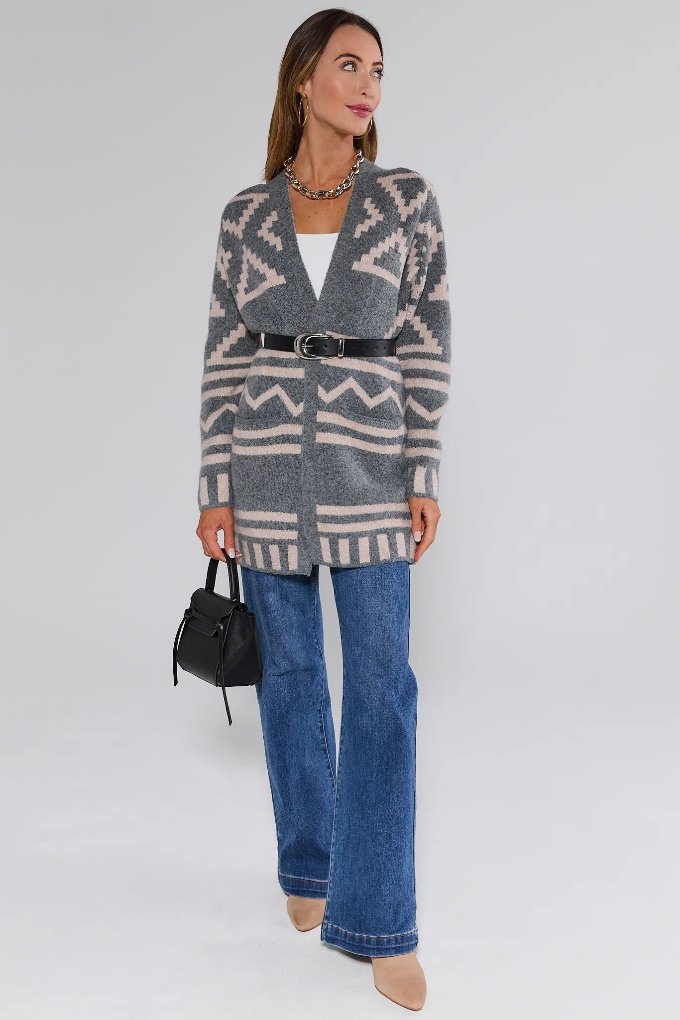 Woman wearing a patterned Helena Cardigan and blue jeans on a white background