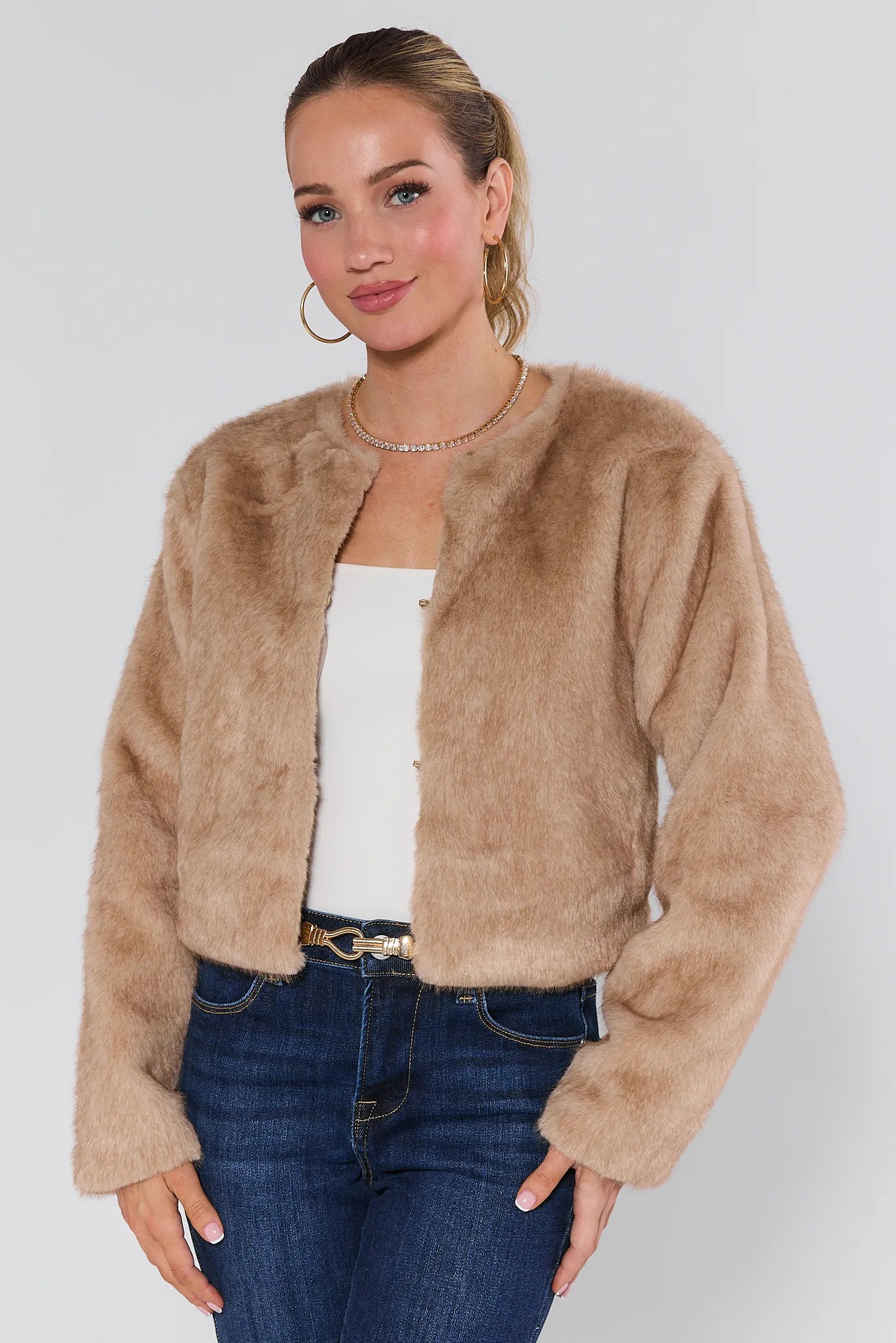 Woman wearing a Tamara Ivory Faux Fur Jacket and blue jeans on a white background